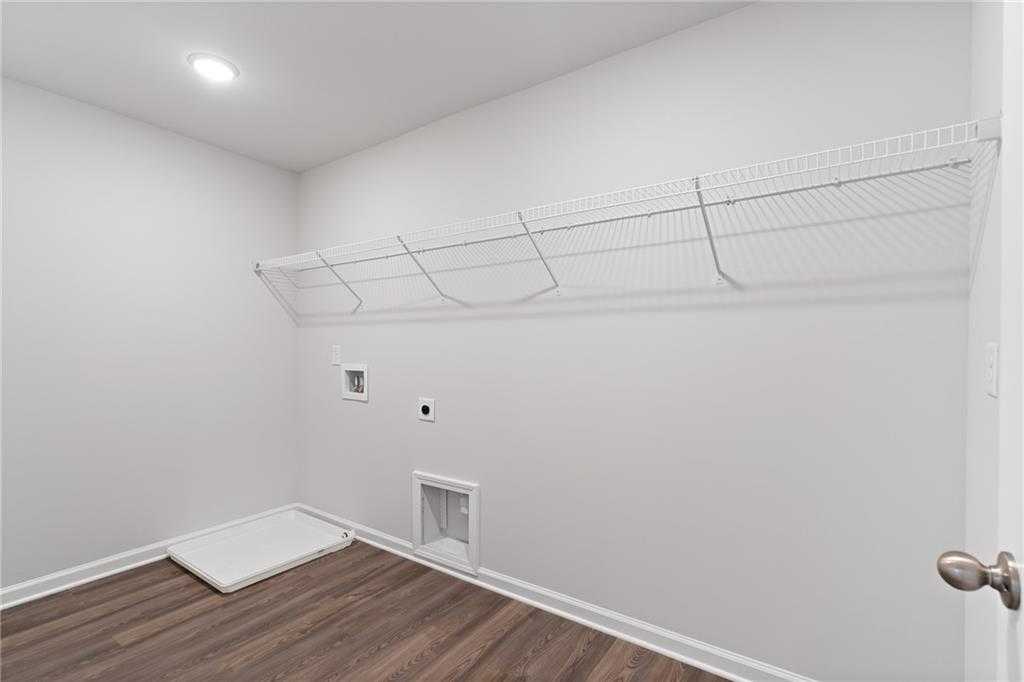 Spacious laundry room with white wire shelving, washer/dryer hookups and hardwood floors in Davidson Homes The Hickory B, Winder, GA