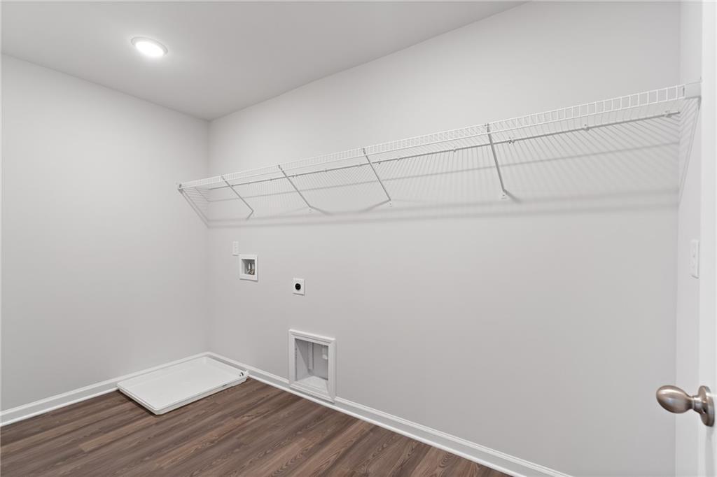 Spacious laundry room with wire shelving, washer-dryer hookups and hardwood floors in Davidson Homes The Hickory A, Winder, GA