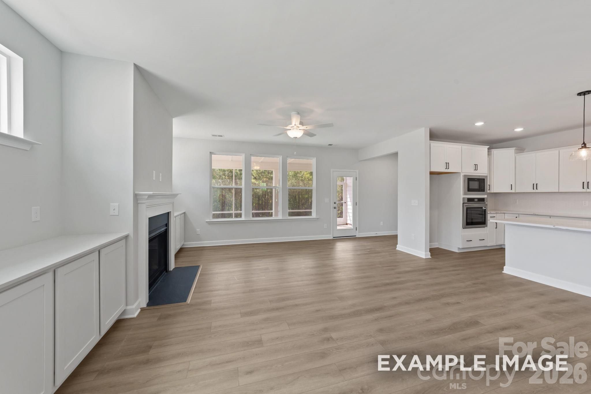 Open-concept living room with fireplace and white kitchen in The Magnolia B floor plan at Windgate, Mooresville, NC.