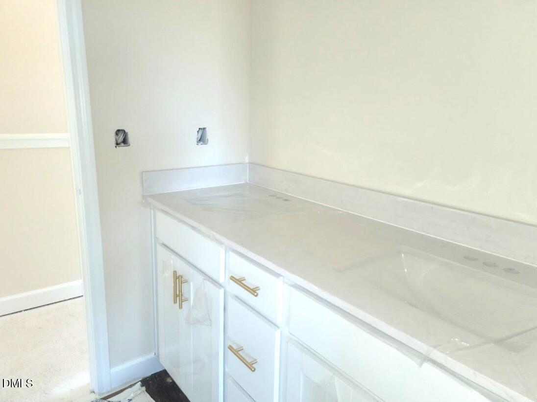 Elegant double-sink vanity with white shaker cabinets, gold hardware, and quartz countertop in Davidson Homes The Cypress B II, Angier NC