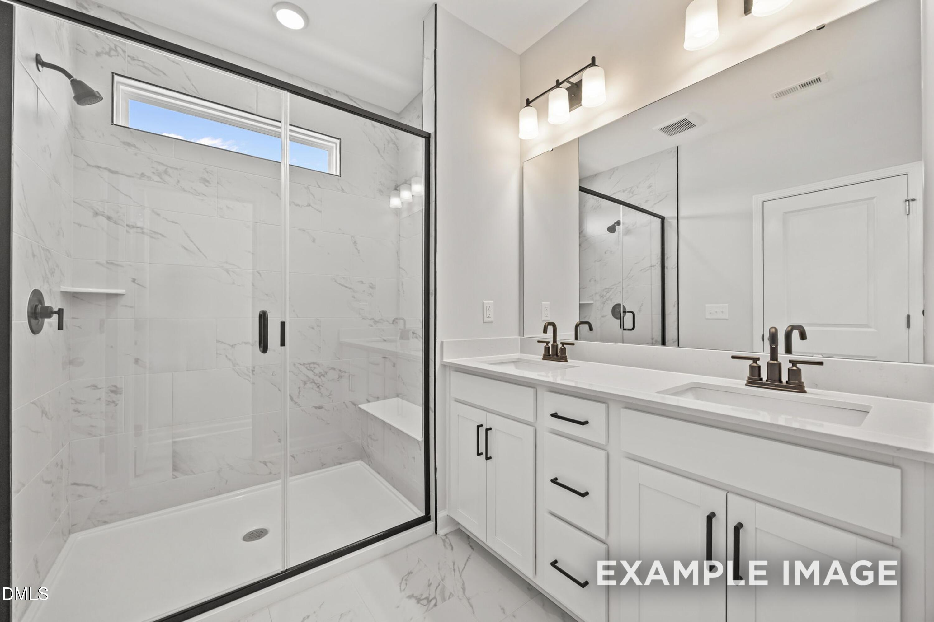 Modern ensuite bathroom with glass-enclosed marble shower and dual vanity in The Alexander B at Forestville Yard, Knightdale.