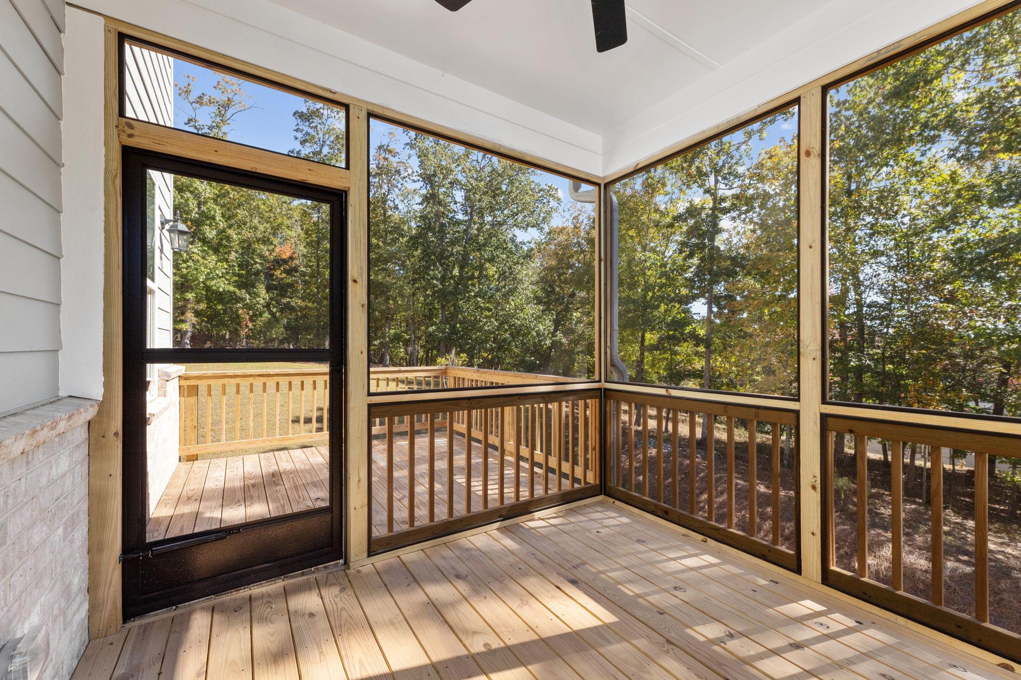 Screened porch with wooden deck, railing, ceiling fan, and tree views at Melody Lakeside Estates in Buford Georgia by Davidson Homes