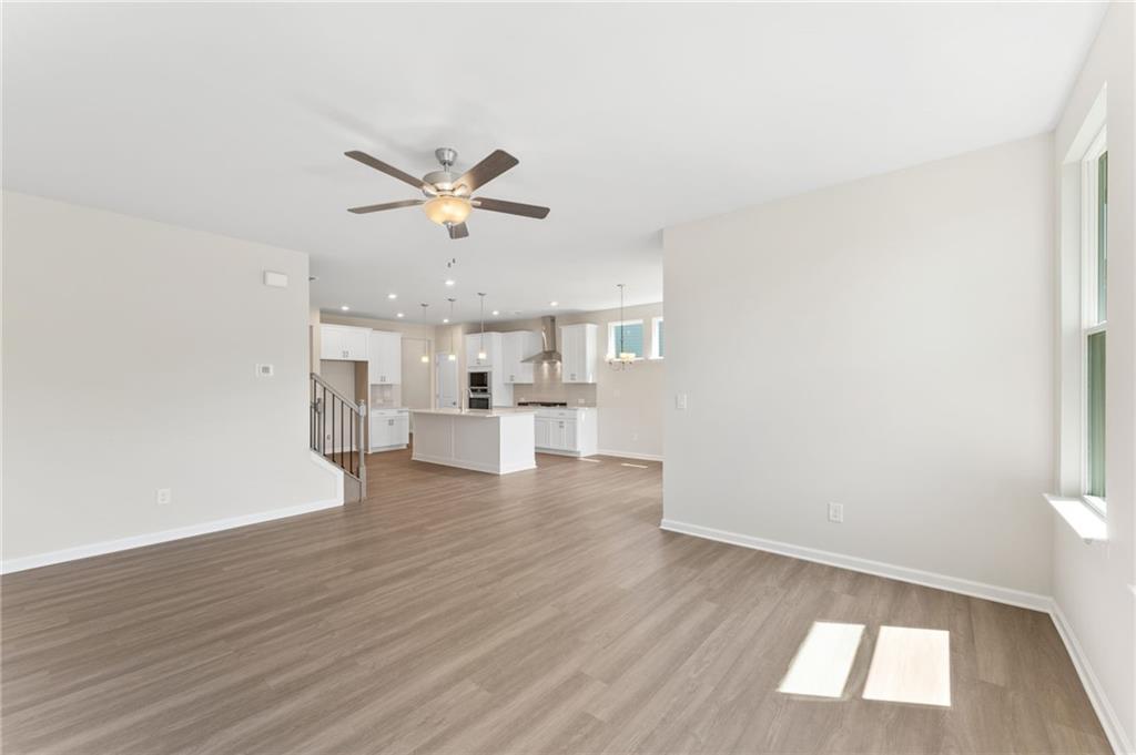 Open-concept kitchen and living area with white island, recessed lights, and ceiling fan in 3-bedroom Davidson Homes The Ash B, Riverwood, Dallas, GA