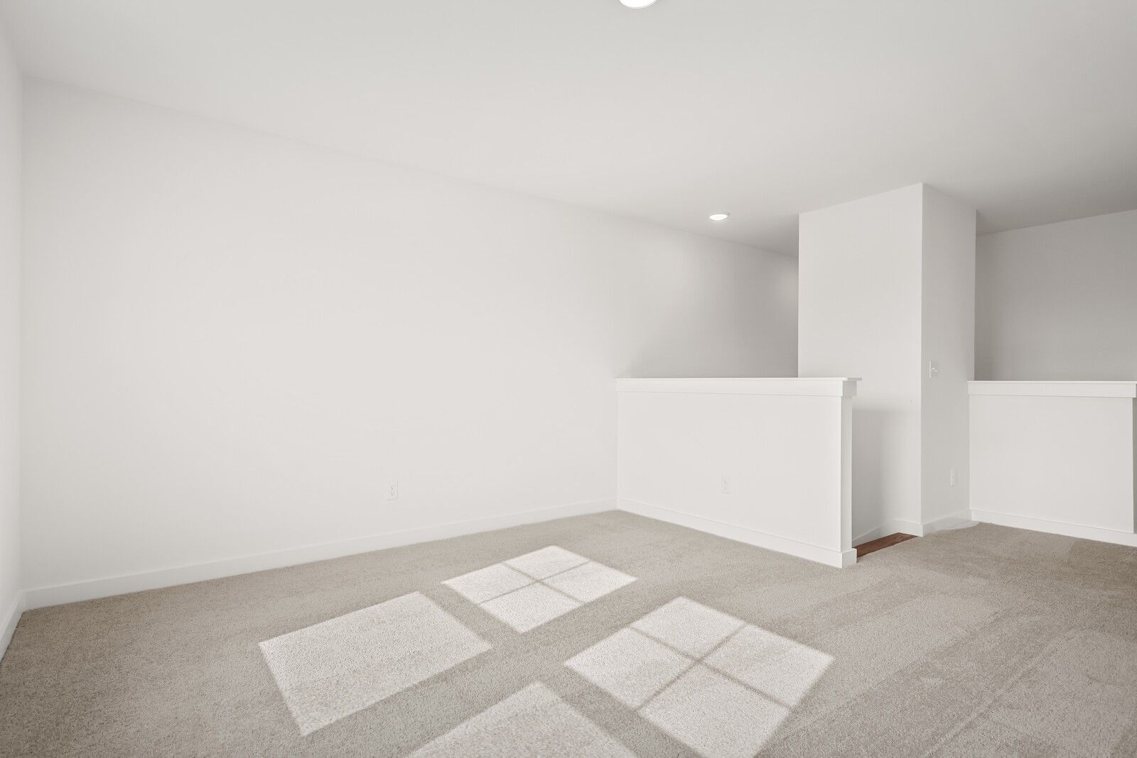 Bright upstairs landing with white railing and beige carpet in Davidson Homes The Logan C, Gallatin, Tennessee