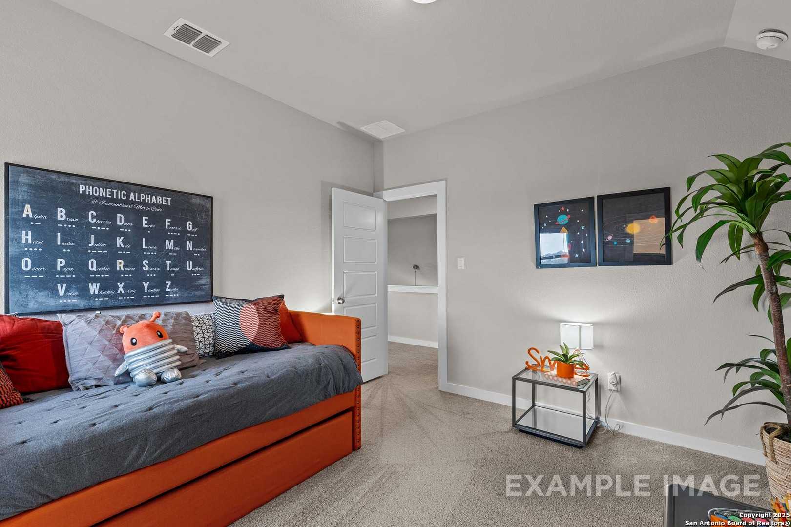 Cozy children's bedroom featuring phonetic alphabet poster, gray trundle bed with orange accents, space art in The Collin B, Seguin, TX