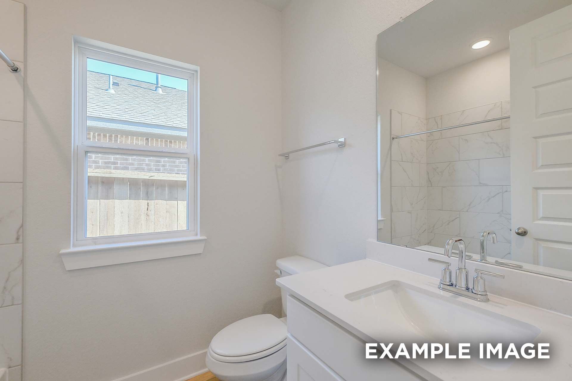 Spacious master bathroom in The Luna K home plan with marble tile shower, white quartz vanity, and large window