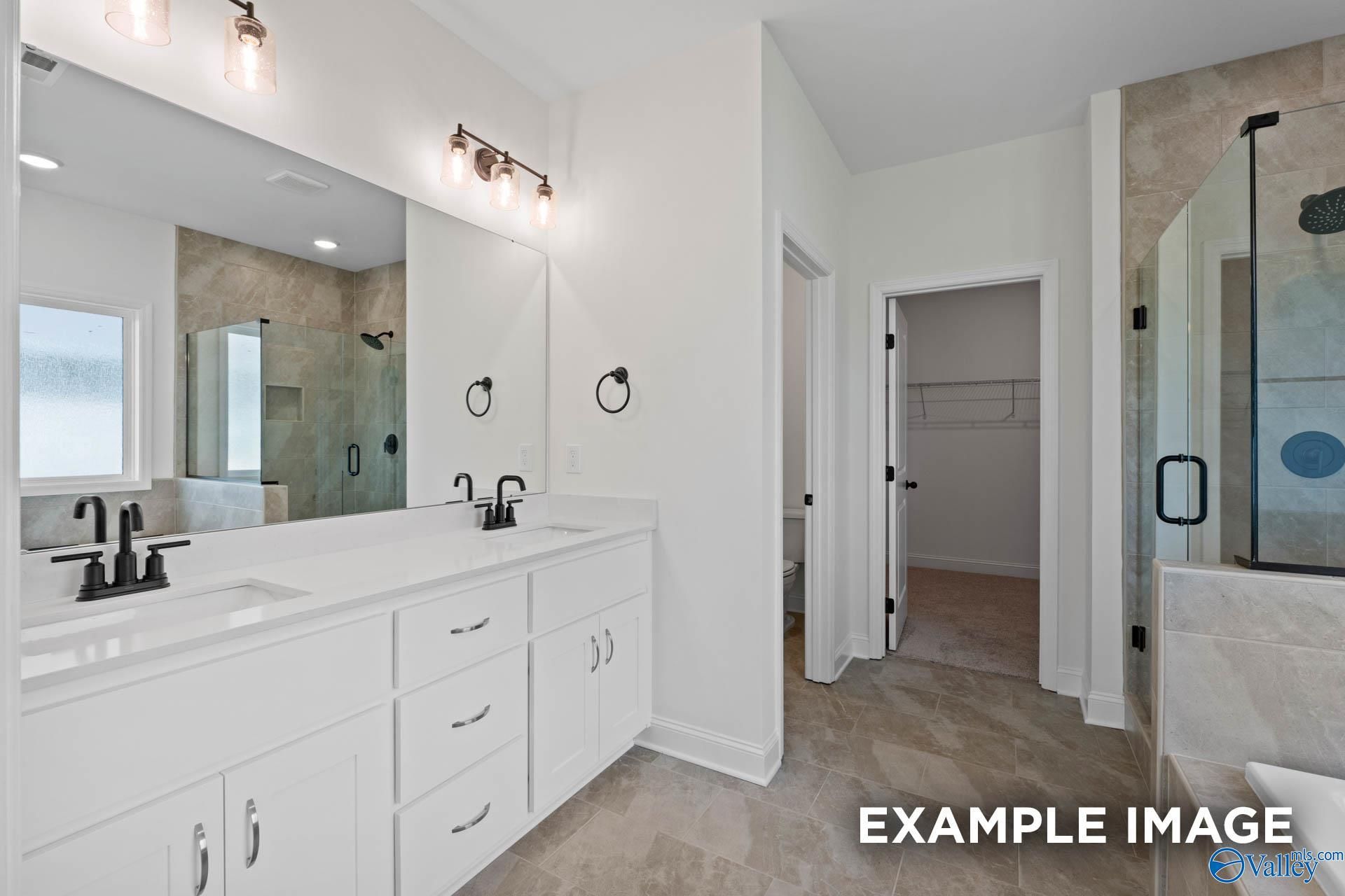 Modern master bathroom with dual vanity, glass-enclosed shower, and walk-in closet in The Rockford B, Briercreek home.