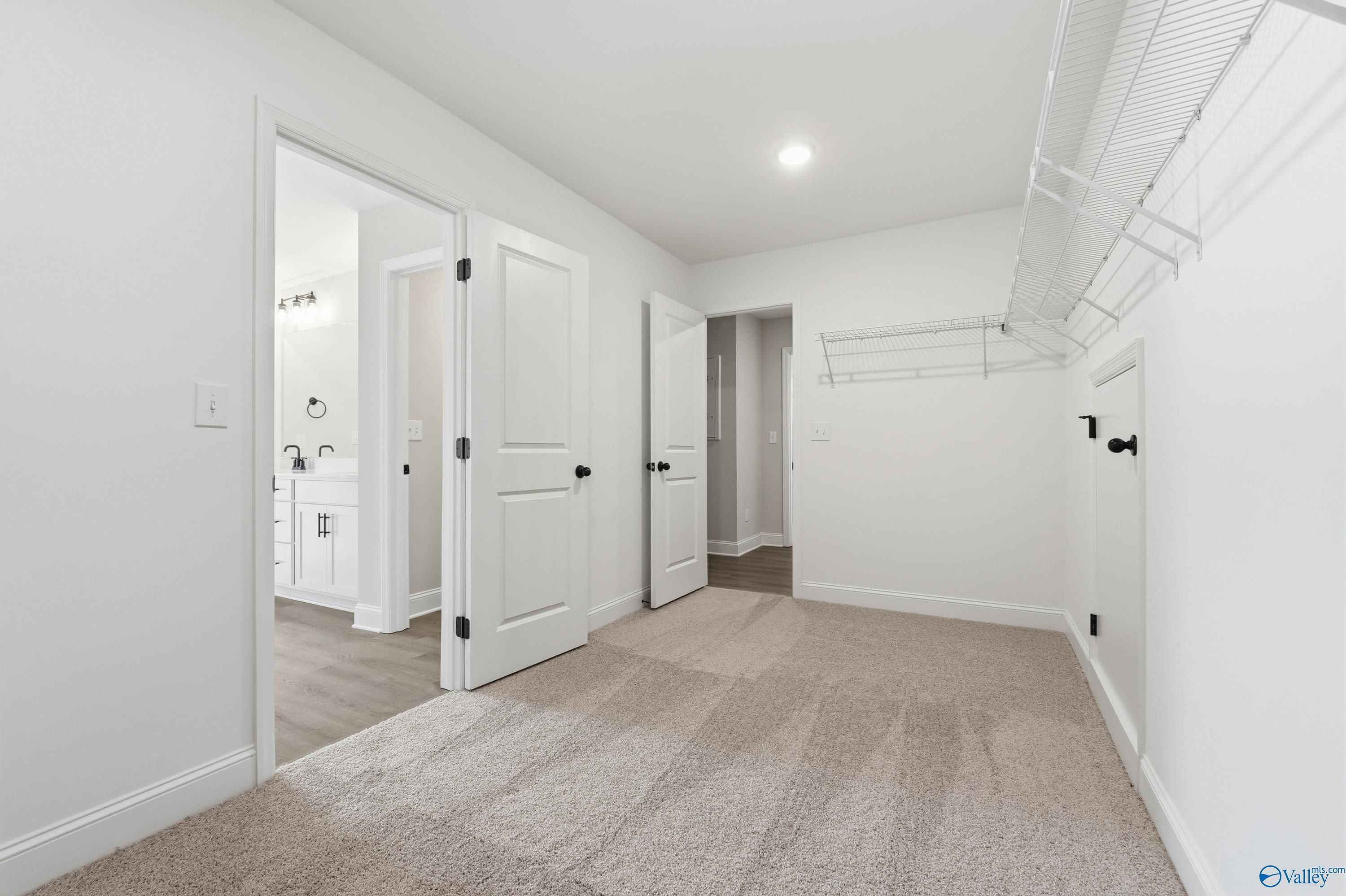 Spacious walk-in closet with wire shelving and open doors to master bathroom vanity in Davidson Homes Chelsea C, Harvest AL
