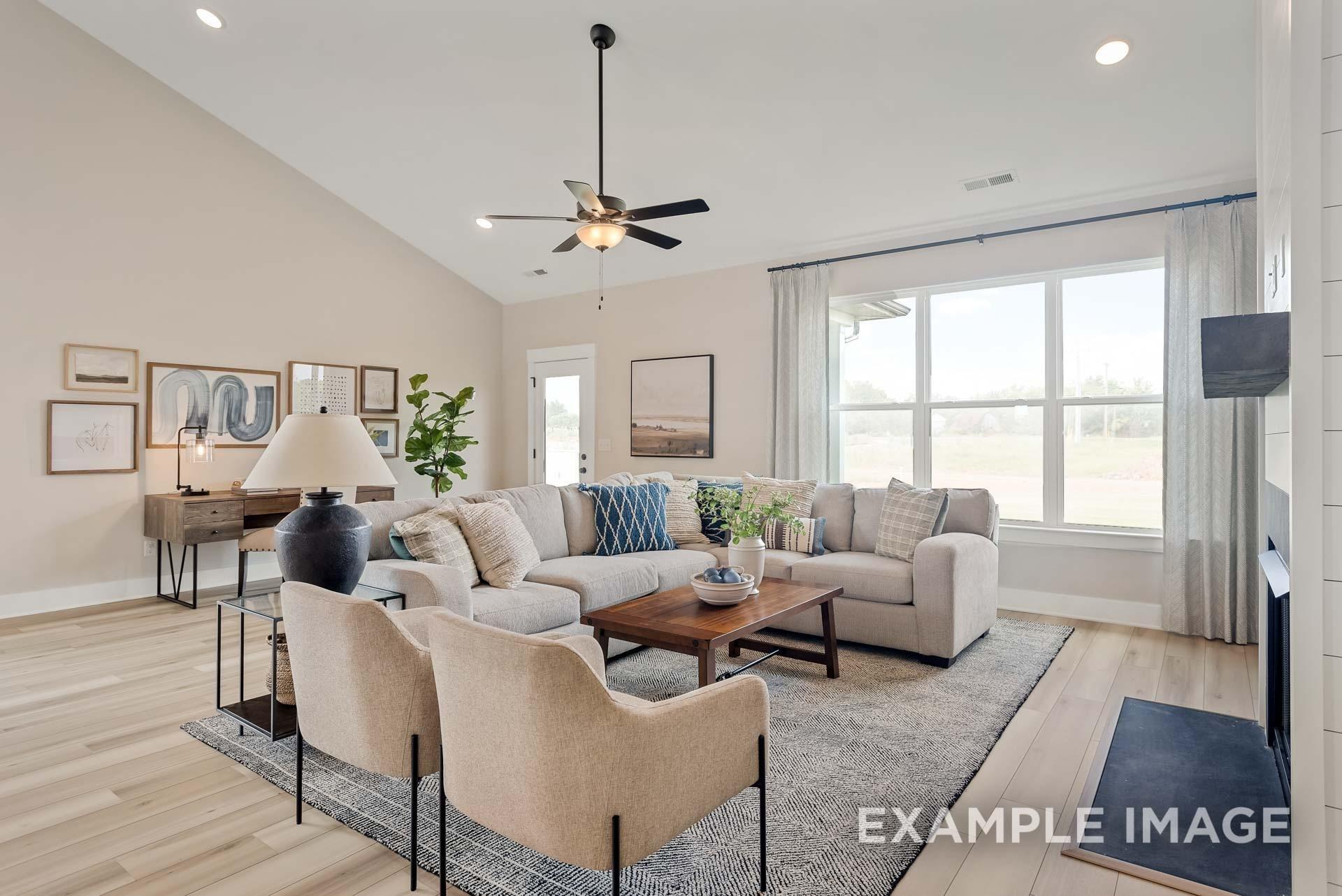 Inviting living room with L-shaped beige sofa, ceiling fan, large windows, and neutral decor in Davidson Homes The Ridgeport, Gallatin, Tennessee