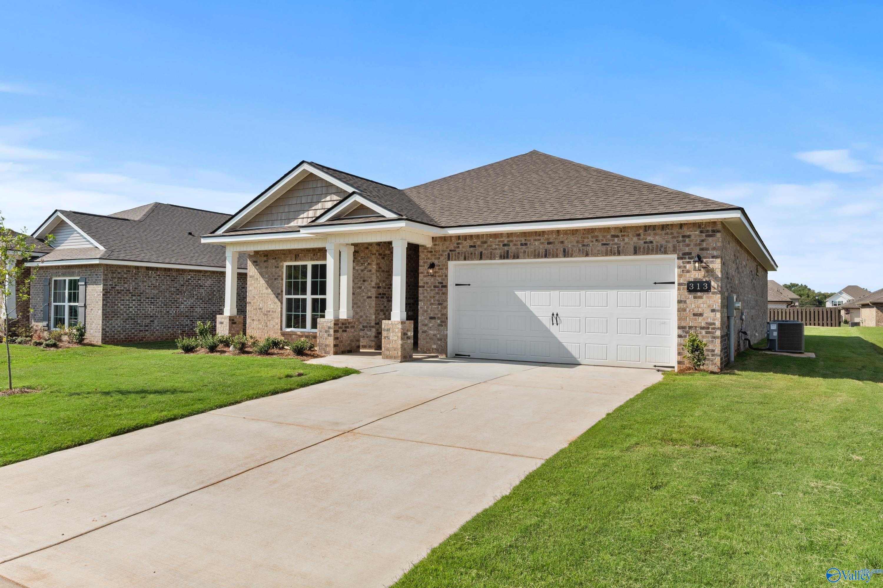 Modern 1-story brick home with gabled roof, 2-car garage, covered porch, and manicured lawn in Clearview, Hazel Green, Alabama