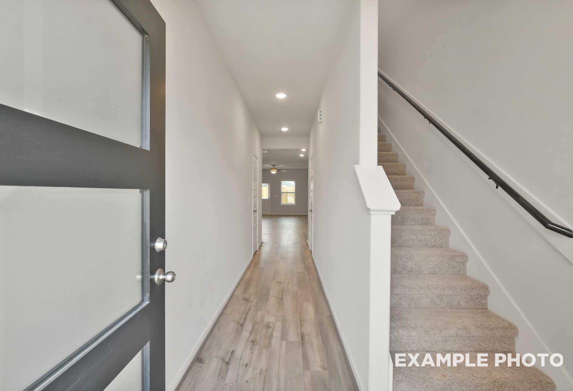 Foyer and staircase in The Brazos by Davidson Homes, featuring gray front door, wood-look flooring, and carpeted stairs