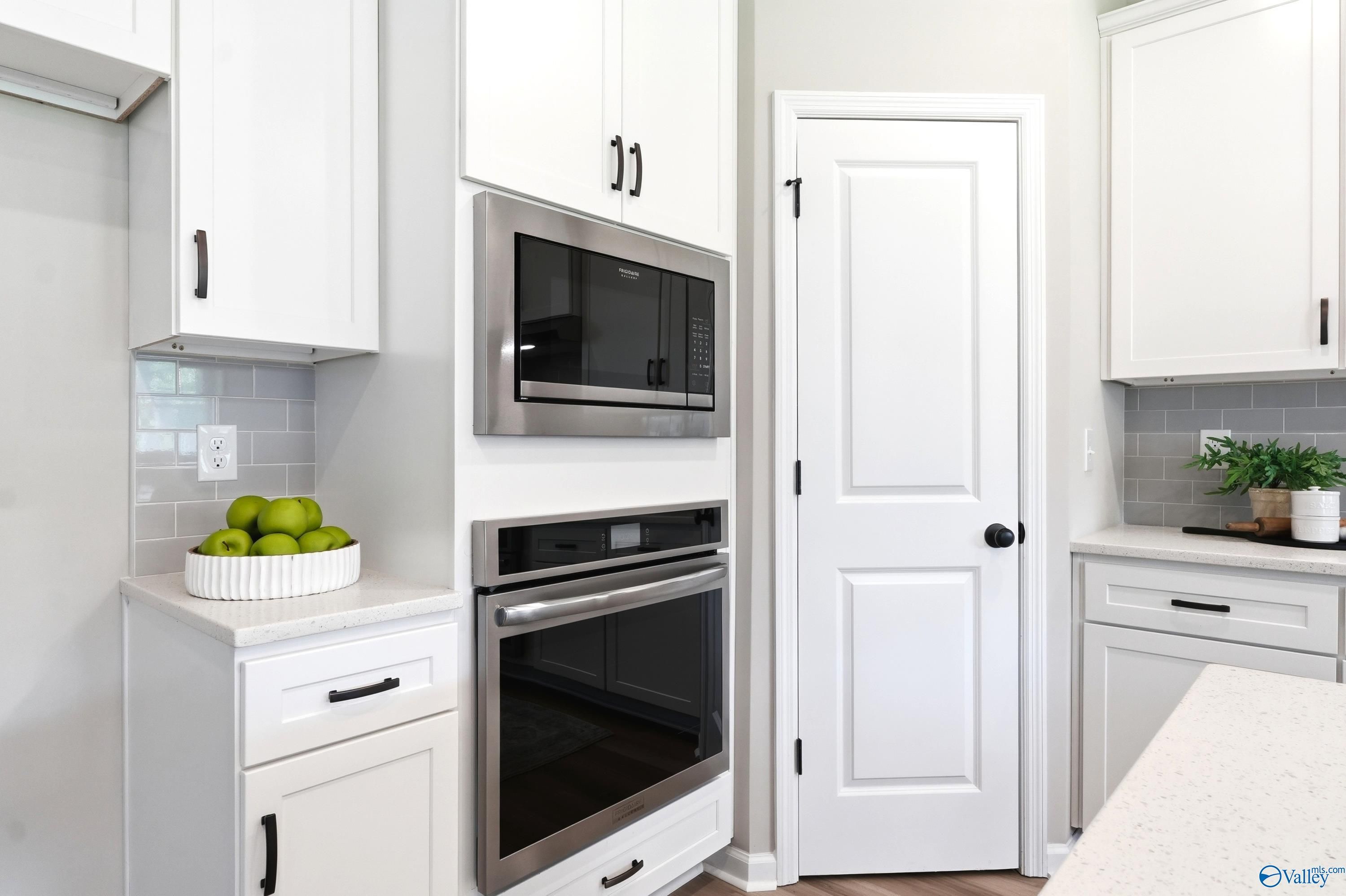 Modern kitchen with stainless steel wall oven, microwave, and white cabinetry in The Dorado home at Riverton Preserve, AL.