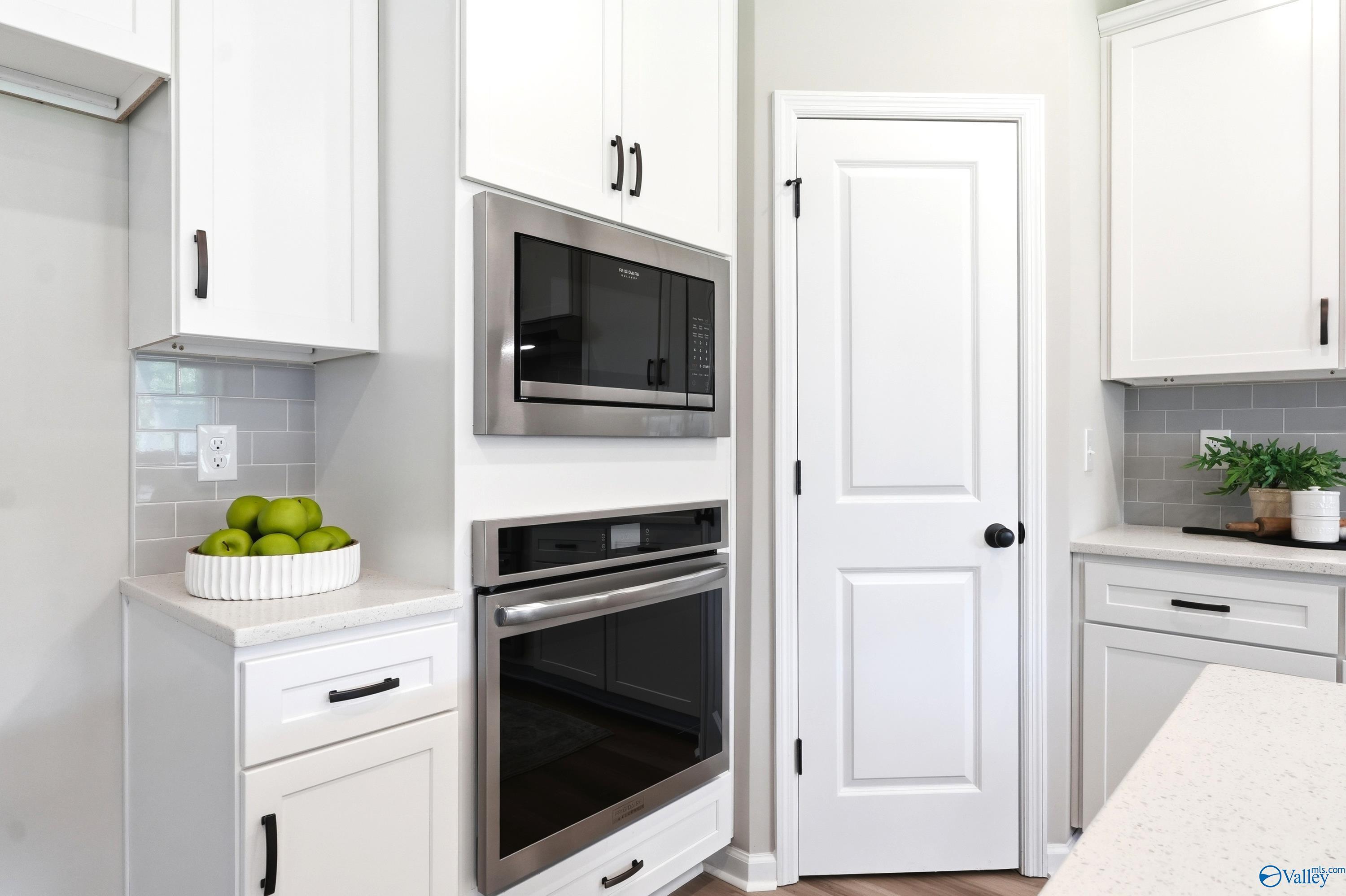 Modern kitchen with stainless steel wall oven, microwave, and white cabinetry in The Dorado home at Riverton Preserve, AL.