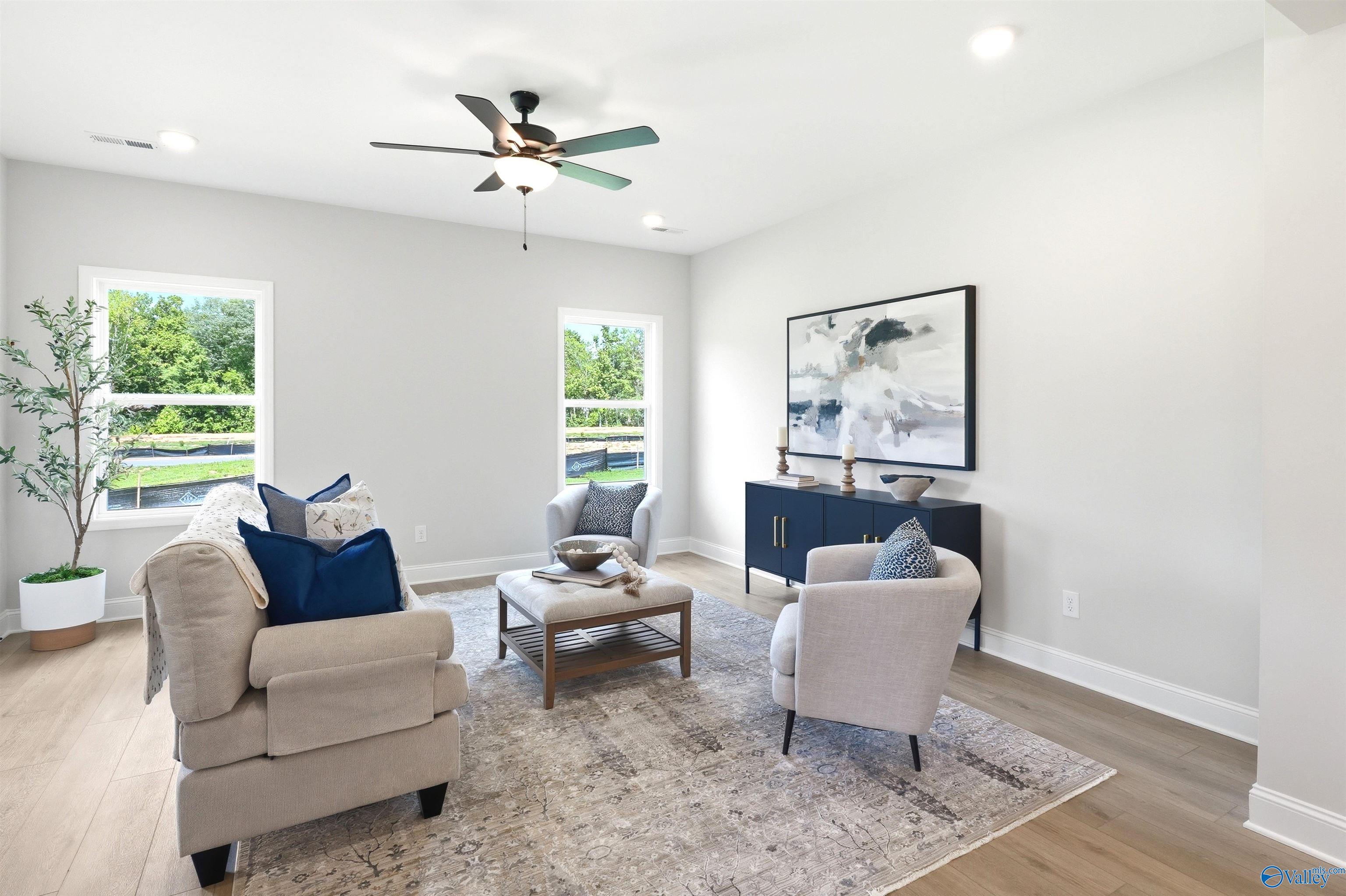Bright living room with beige sofa, armchairs, ceiling fan, and hardwood floors in Davidson Homes The Russell A, Huntsville, Alabama