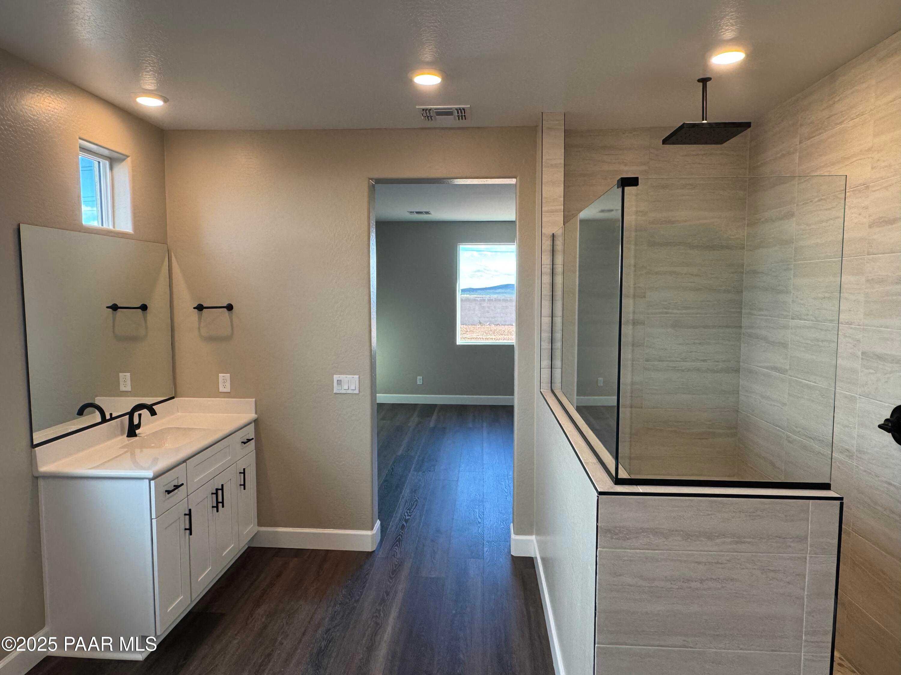 Modern master bathroom featuring double vanity, frameless glass shower, and desert view window in Evermore Homes The Sunrise A, Prescott Valley