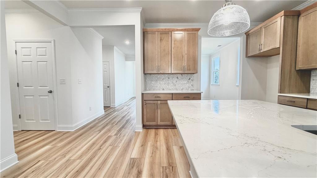 Modern kitchen with quartz island and wood cabinetry in The Glenwood A floor plan at Wehunt Meadows, Hoschton, GA.