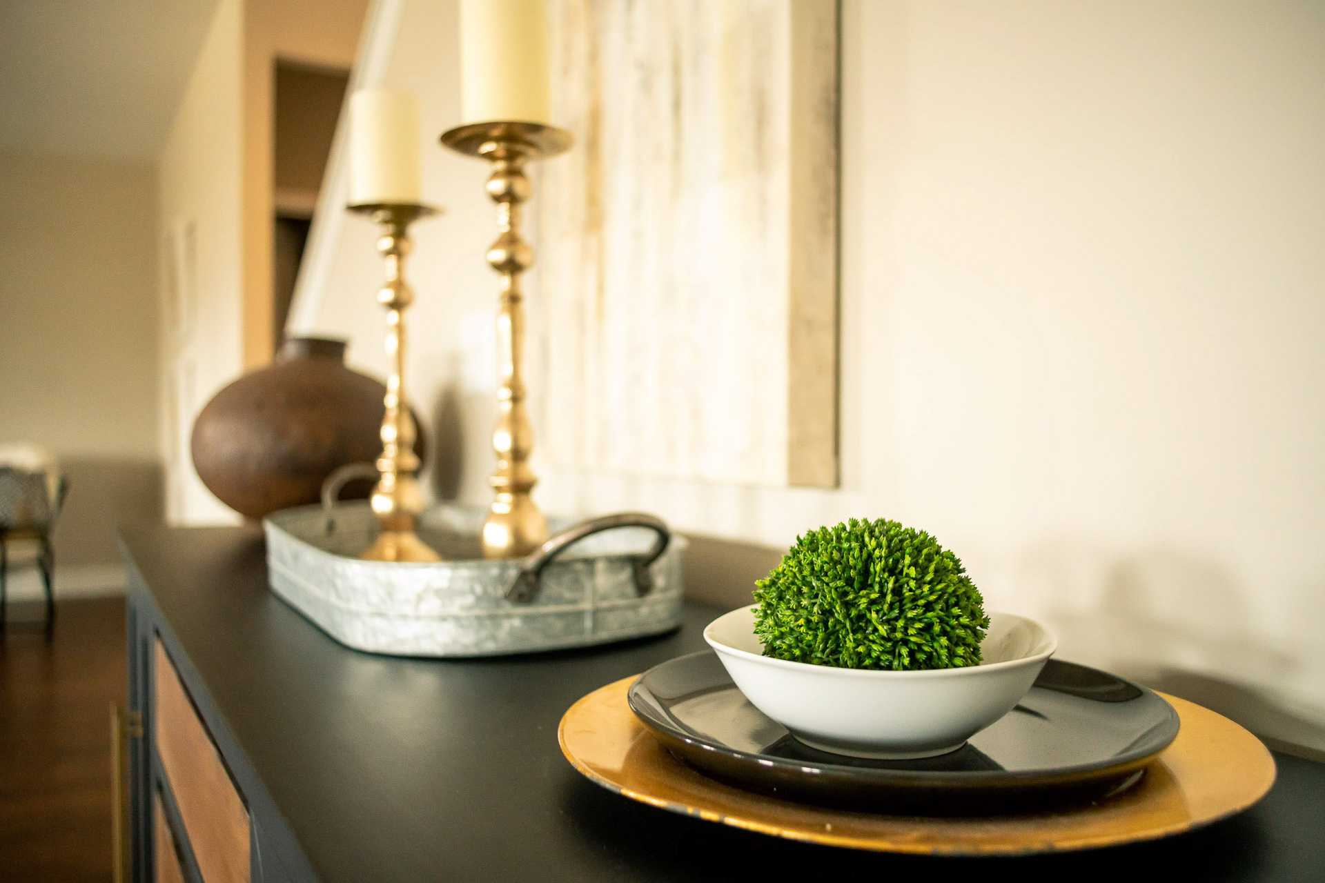 Elegant console table in Summer Pointe Madison AL home with gold candlesticks, white candles, green boxwood ball in bowl, and galvanized tray