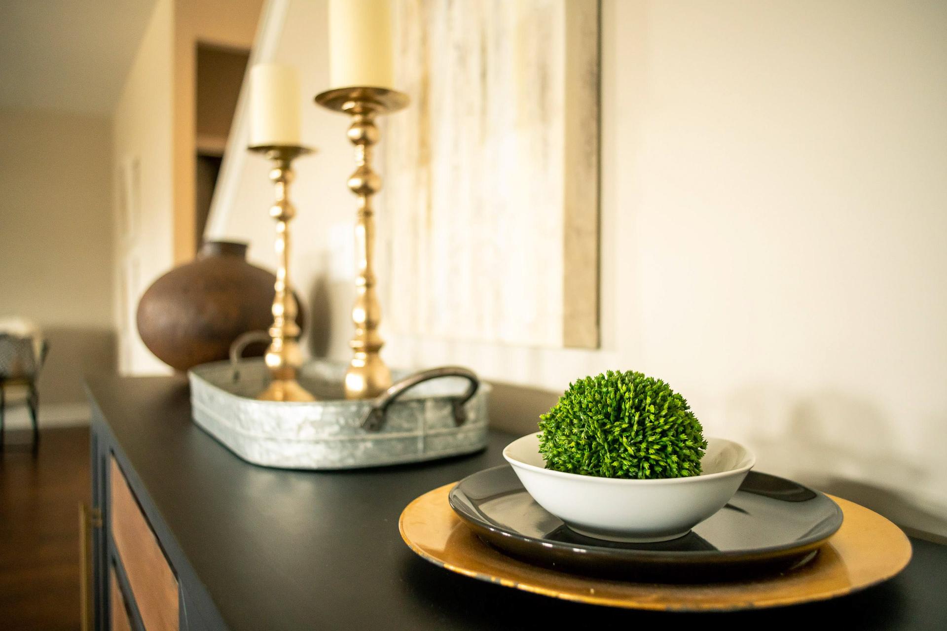 Elegant console table in Summer Pointe Madison AL home with gold candlesticks, white candles, green boxwood ball in bowl, and galvanized tray