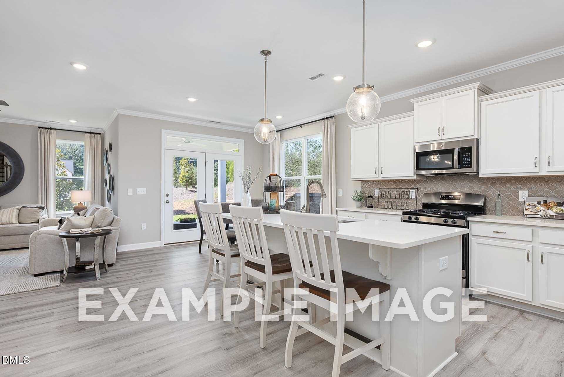 Bright open-concept kitchen with white island, stainless appliances, dining area, and living room in Davidson Homes The Ash B, Lillington, NC