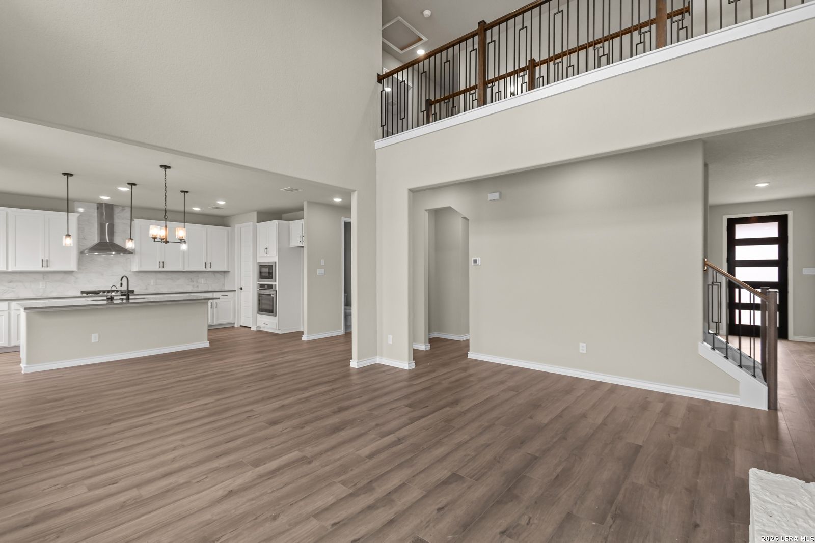 Open-concept living room with two-story ceiling and kitchen in The Danbury H model home at The Reserve at Potranco Oaks.