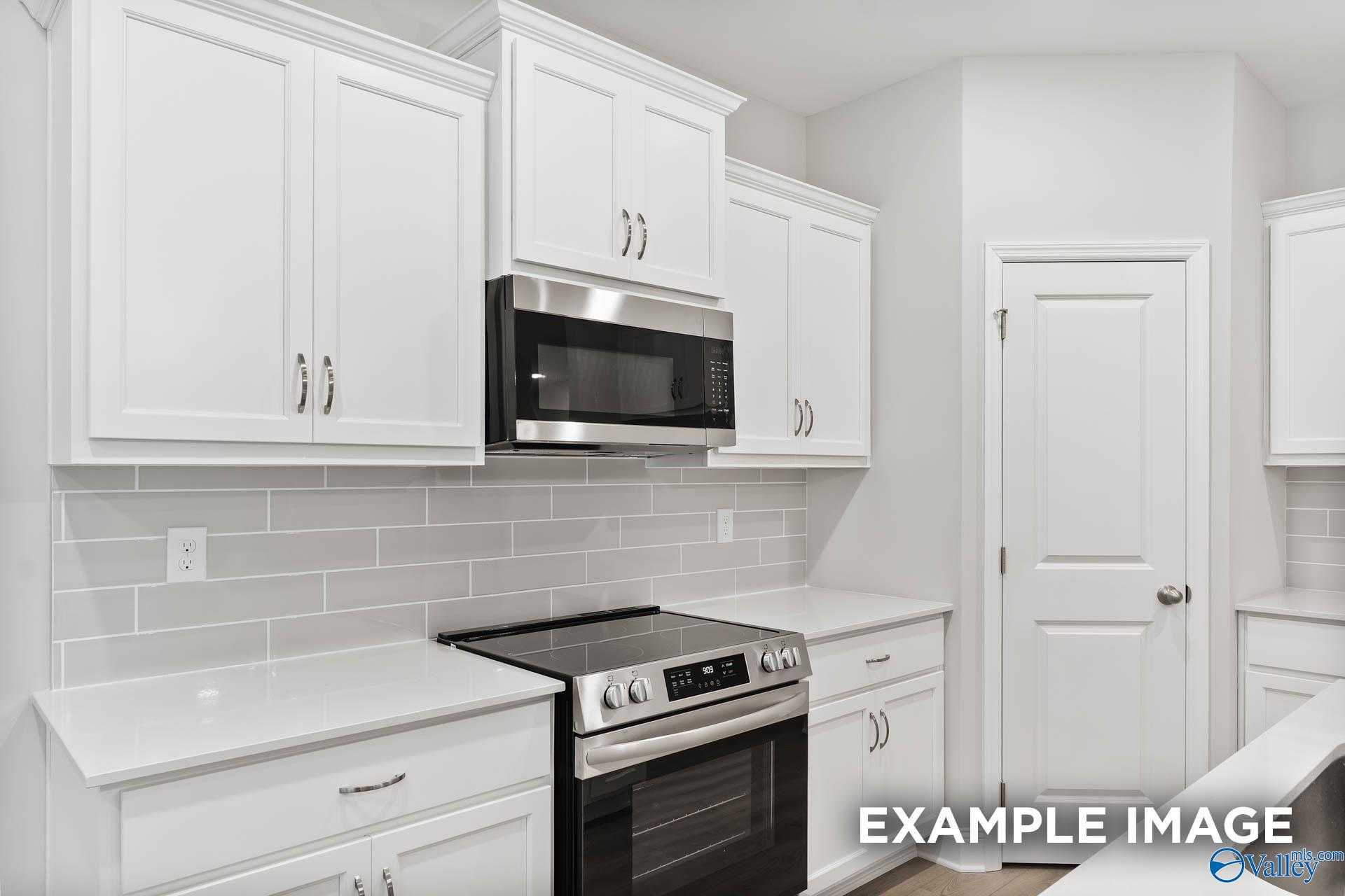 Modern kitchen with white shaker cabinets, stainless steel microwave and range, subway tile backsplash in Davidson Homes The Asheville C, Huntsville AL