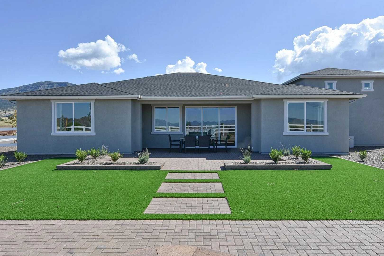 Modern single-story home patio at Morningstar in Prescott Valley AZ with outdoor seating, landscaped yard, and mountain views
