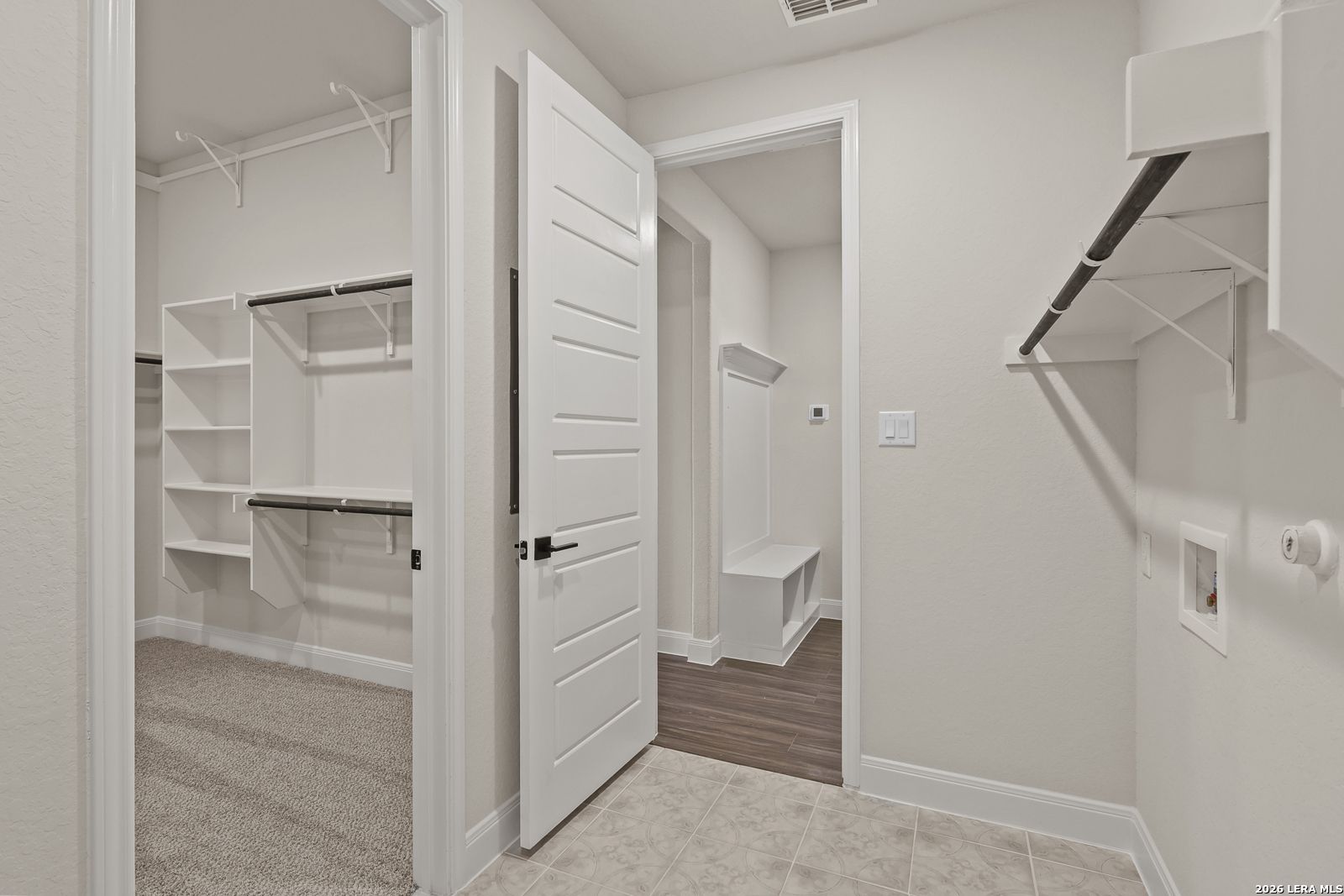 Walk-in closet and laundry area with built-in bench in The Summerlin B floor plan by Davidson Homes in Castroville, Texas.