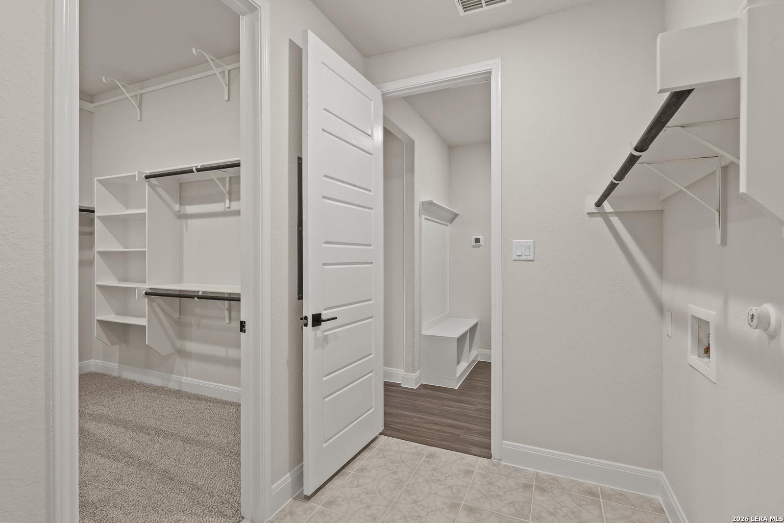 Walk-in closet and laundry area with built-in bench in The Summerlin B floor plan by Davidson Homes in Castroville, Texas.