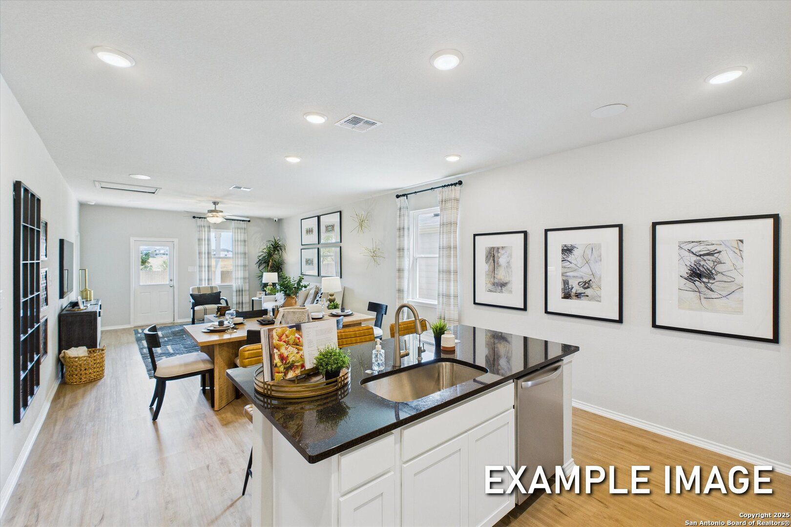 Open-concept kitchen with black granite island, white cabinets, and adjacent dining-living area in Davidson Homes The Sabine B, San Antonio, Texas