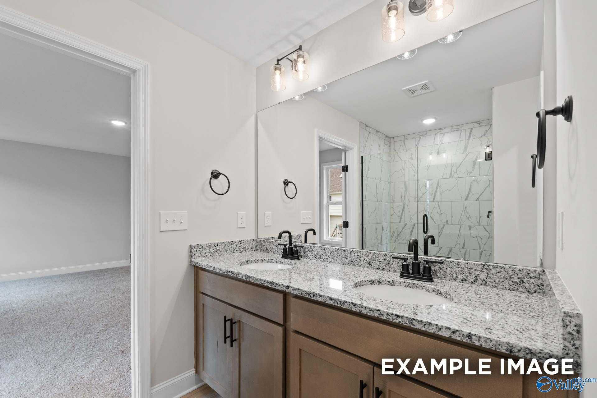 Modern master bathroom with double granite vanity, subway tile shower, and wooden cabinets in Davidson Homes The Camden D, Huntsville