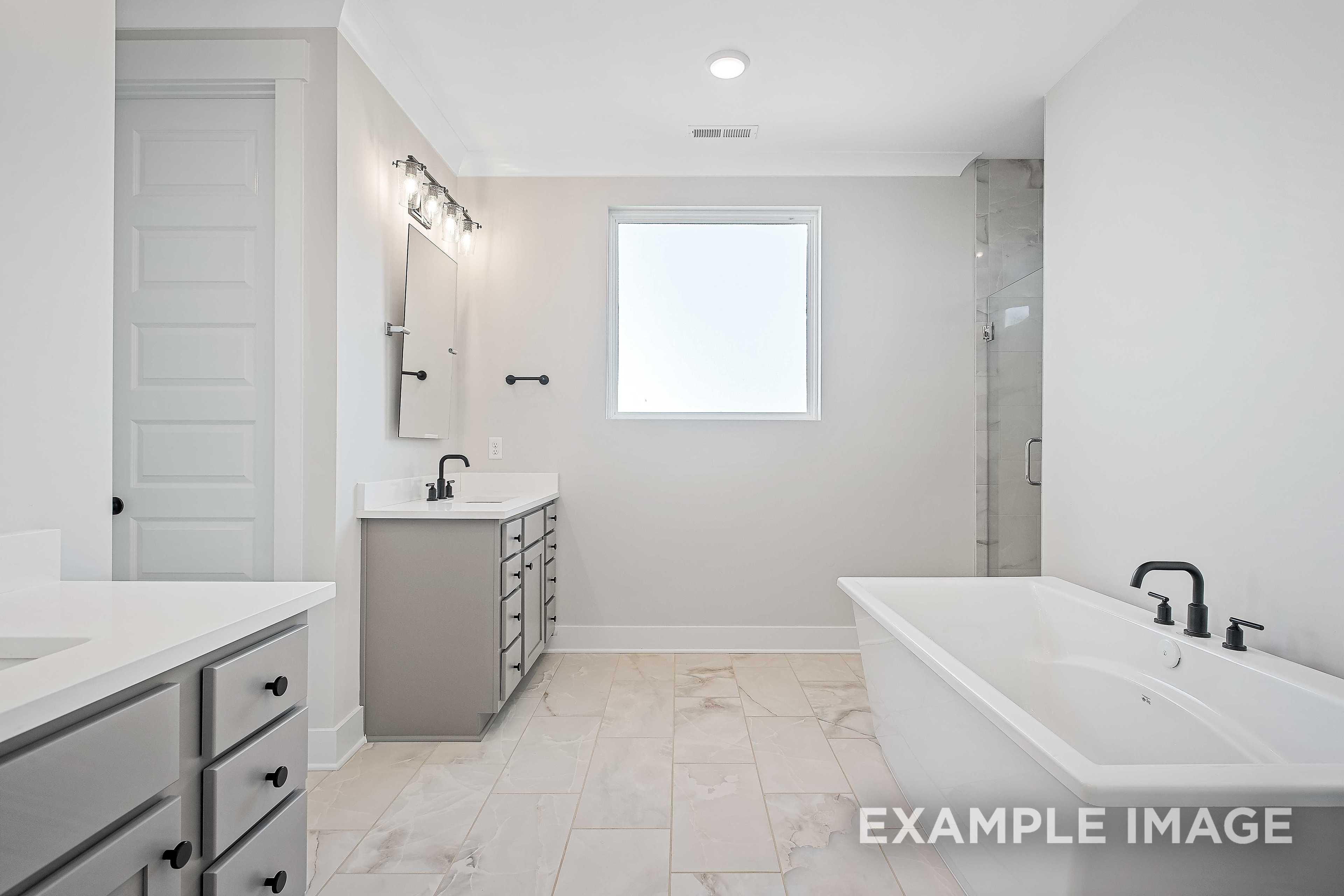 Spacious master bathroom in The Alston A with freestanding tub, walk-in shower, double gray vanity, large window