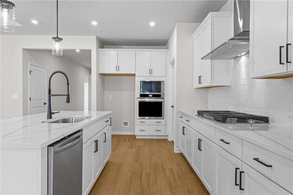 Modern white kitchen with quartz island, stainless steel appliances, subway tile backsplash in Davidson Homes The Edison A, Loganville, GA
