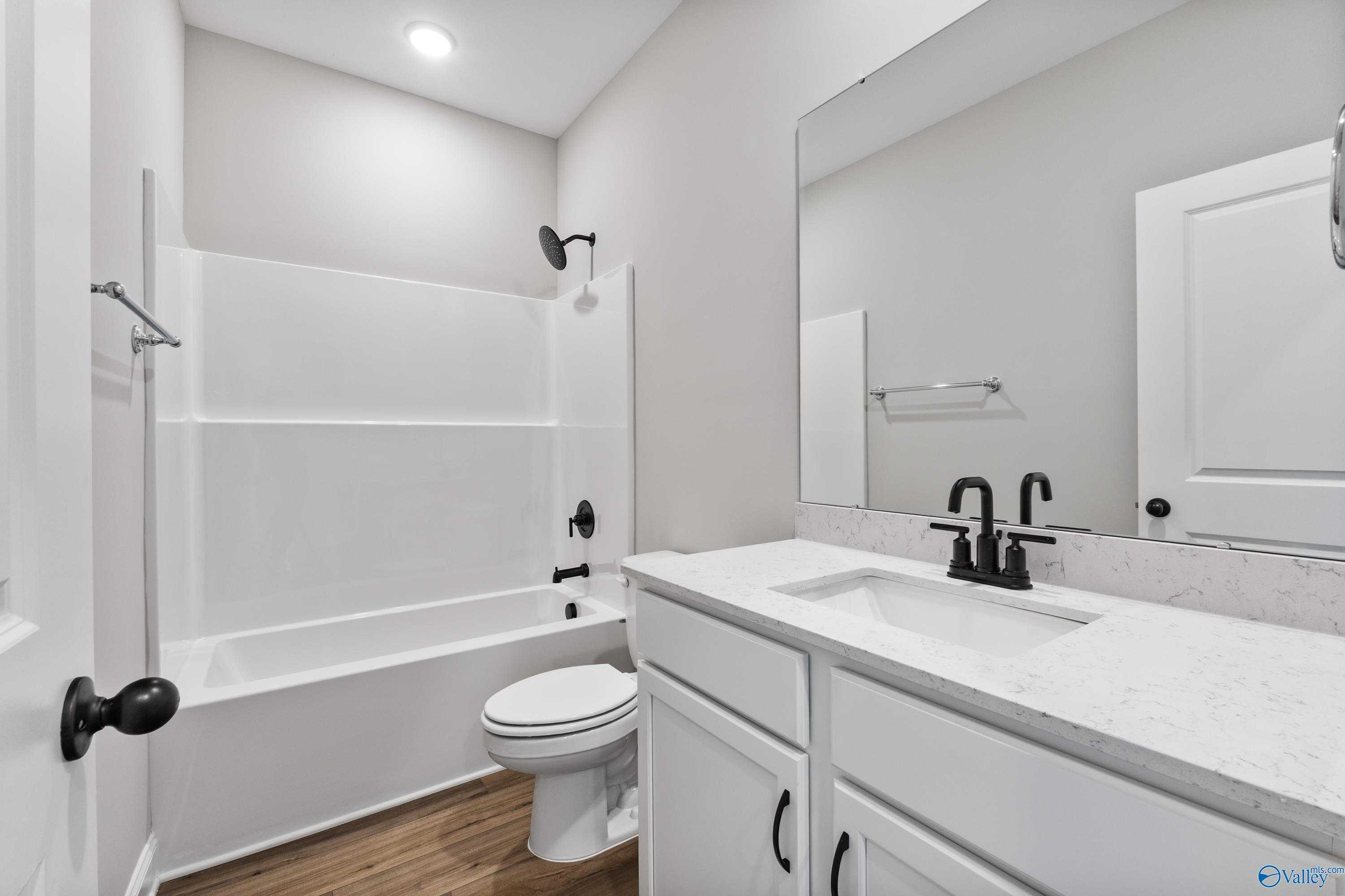 Modern bathroom with white tub-shower combo, single vanity sink, toilet, and gray walls in Davidson Homes The Franklin B, Hazel Green, AL