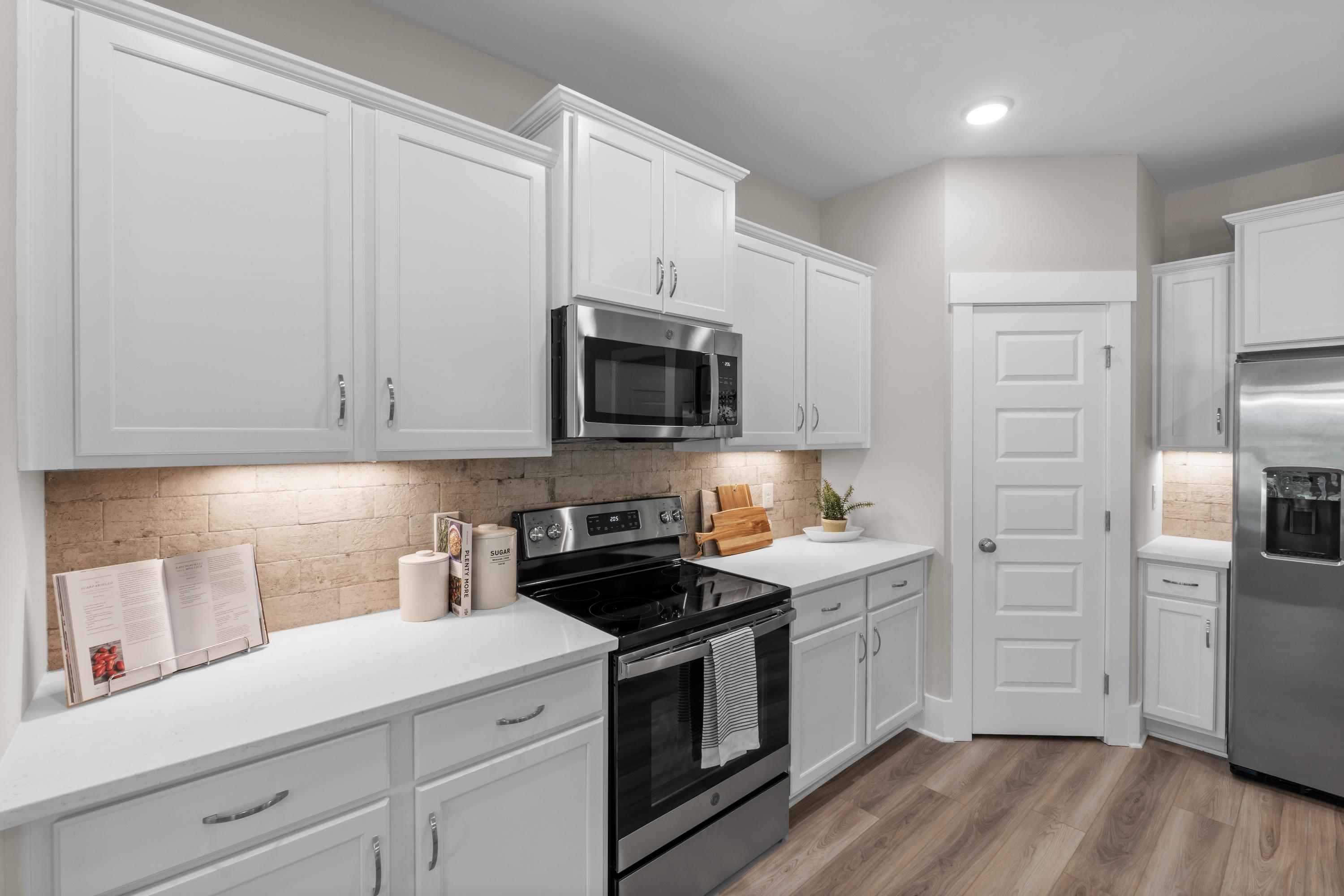 Modern kitchen at The Highlands in Arab Alabama with white shaker cabinets stainless steel appliances subway tile backsplash and hardwood floors