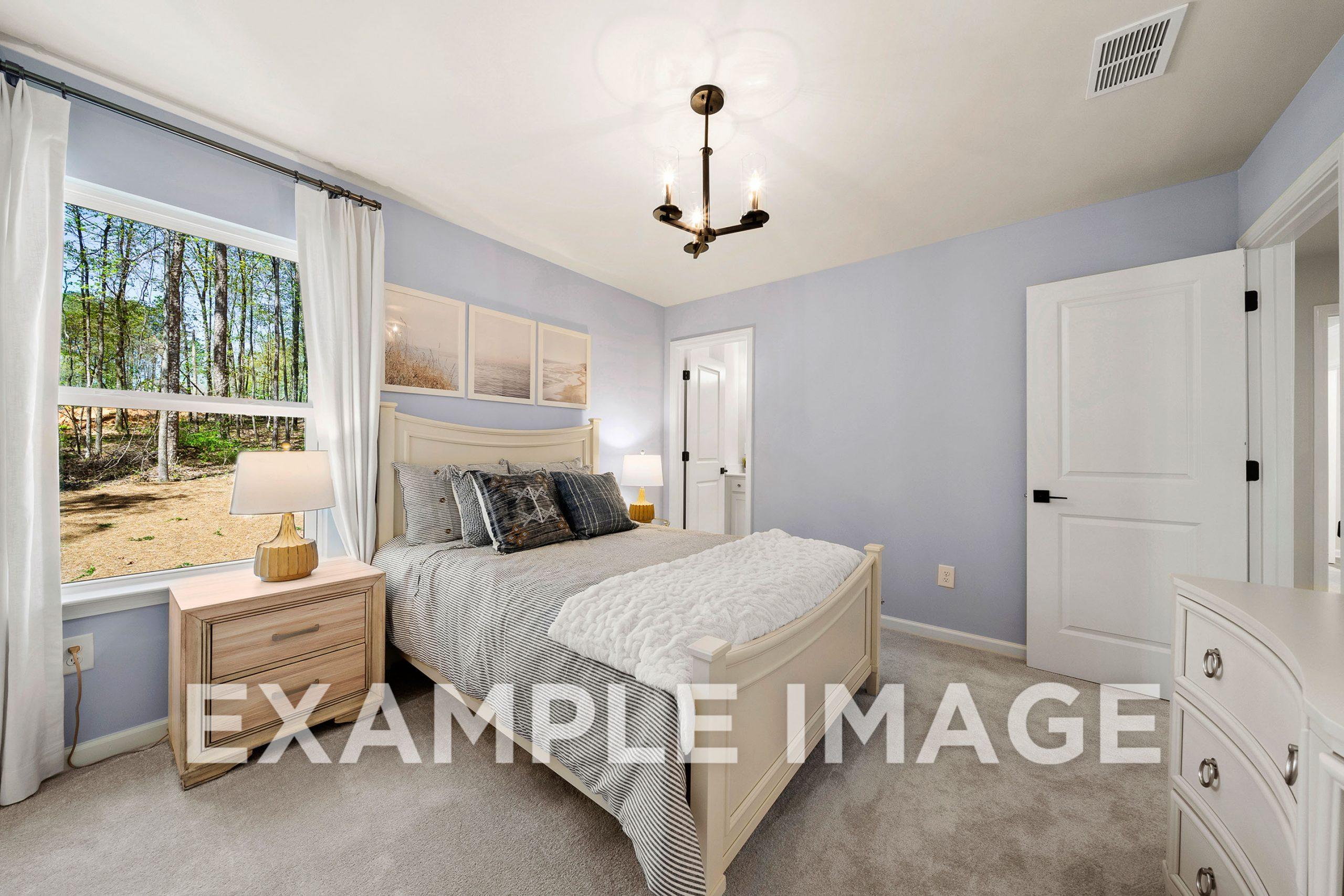 Spacious master bedroom in The Hickory B featuring light blue walls, king bed with white duvet, chandelier, and tree-view window