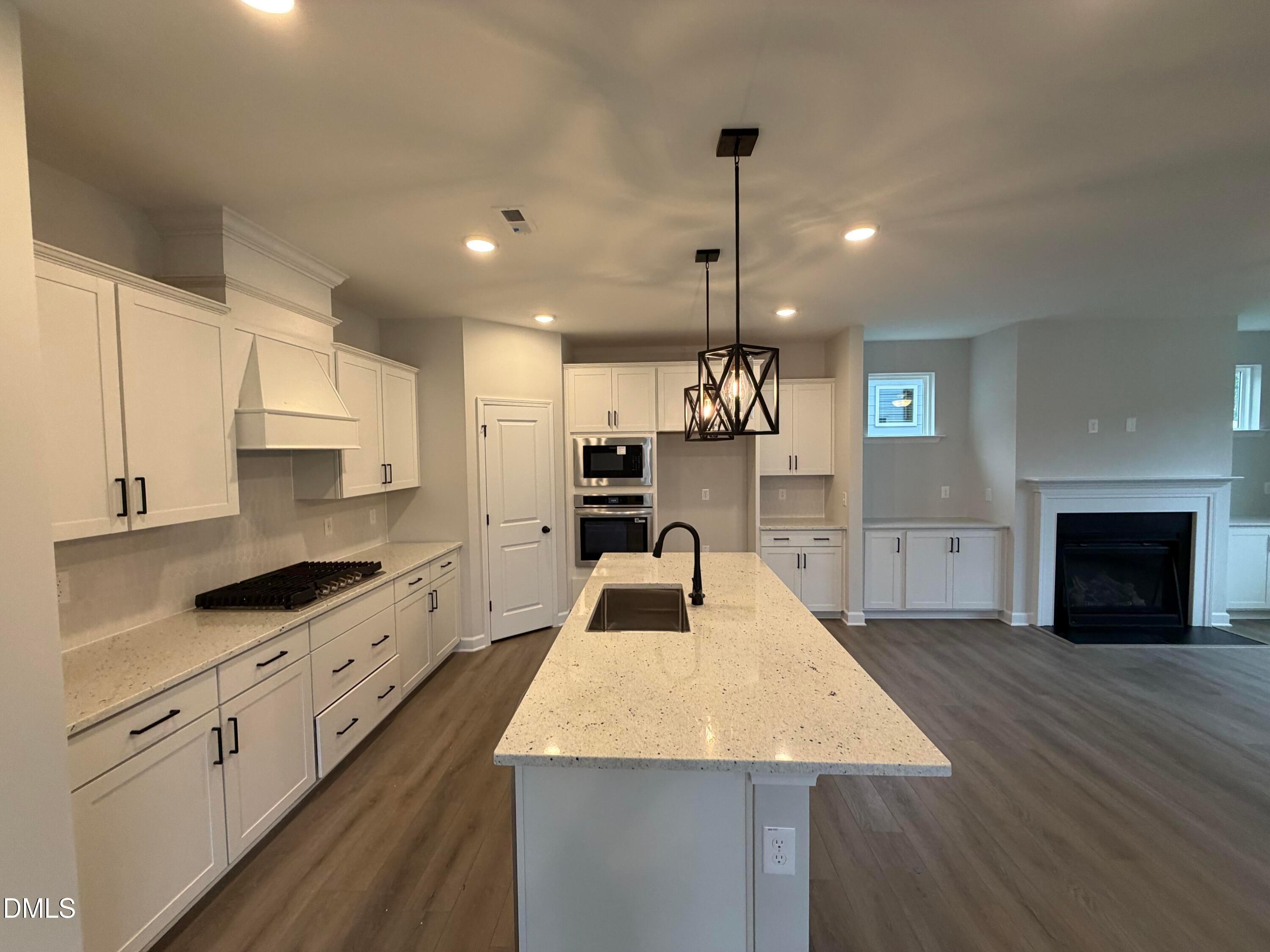 Open-concept kitchen with white cabinetry, quartz island, and gas cooktop in Davidson Homes The Preston C, Wendell Ridge, NC