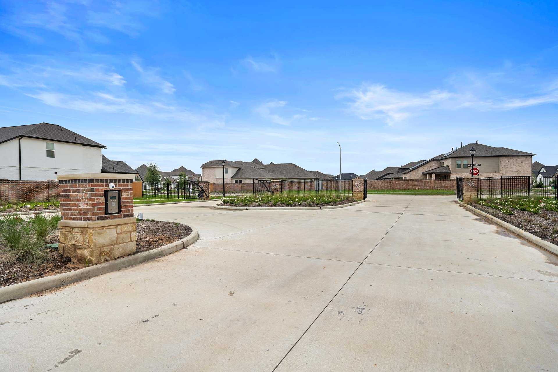 Elegant gated entrance at Sunterra in Katy TX by Davidson Homes with brick stone pillars lush landscaping and modern homes
