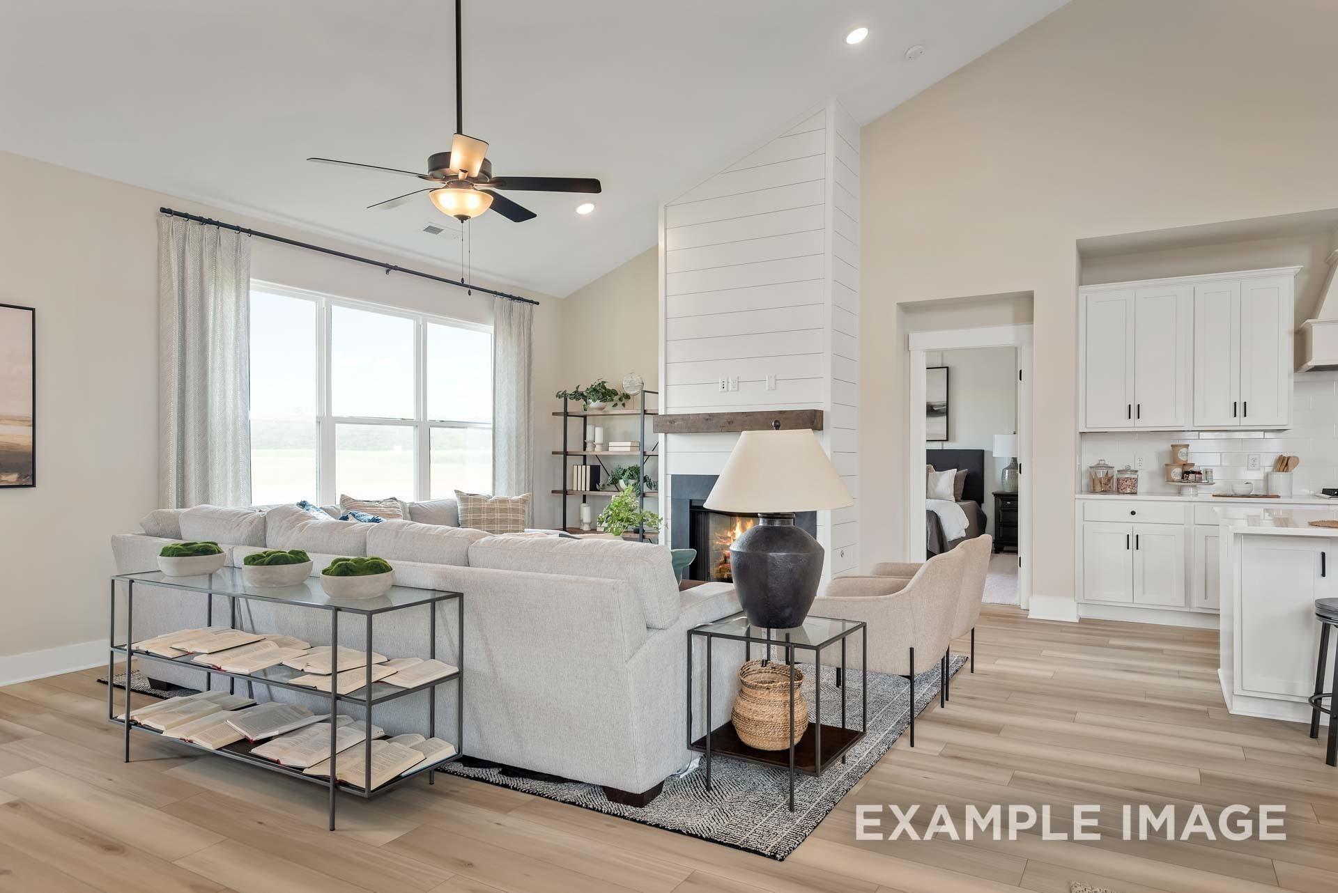 Cozy living room with shiplap fireplace, large windows, and open kitchen in The Ridgeport 4-bedroom home, Gallatin, Tennessee