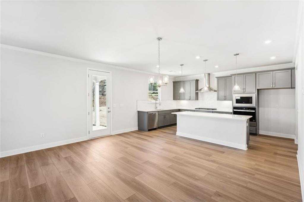 Modern open kitchen with white island, gray shaker cabinets, stainless appliances, hardwood floors in Davidson Homes Hickory C, Hoschton GA