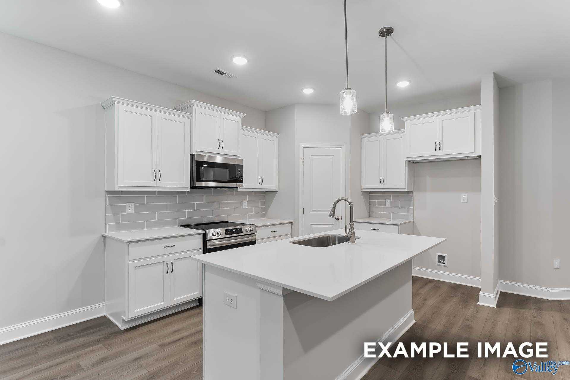 Bright modern kitchen with white shaker cabinets, quartz island, stainless appliances, subway tile in Davidson Homes The Asheville C, Huntsville, AL
