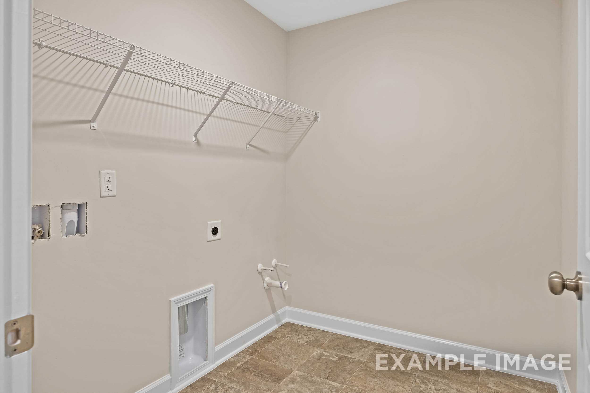 Spacious laundry room in The Preston A home featuring wire shelving, washer/dryer hookups, utility sink, beige walls, and tiled floor
