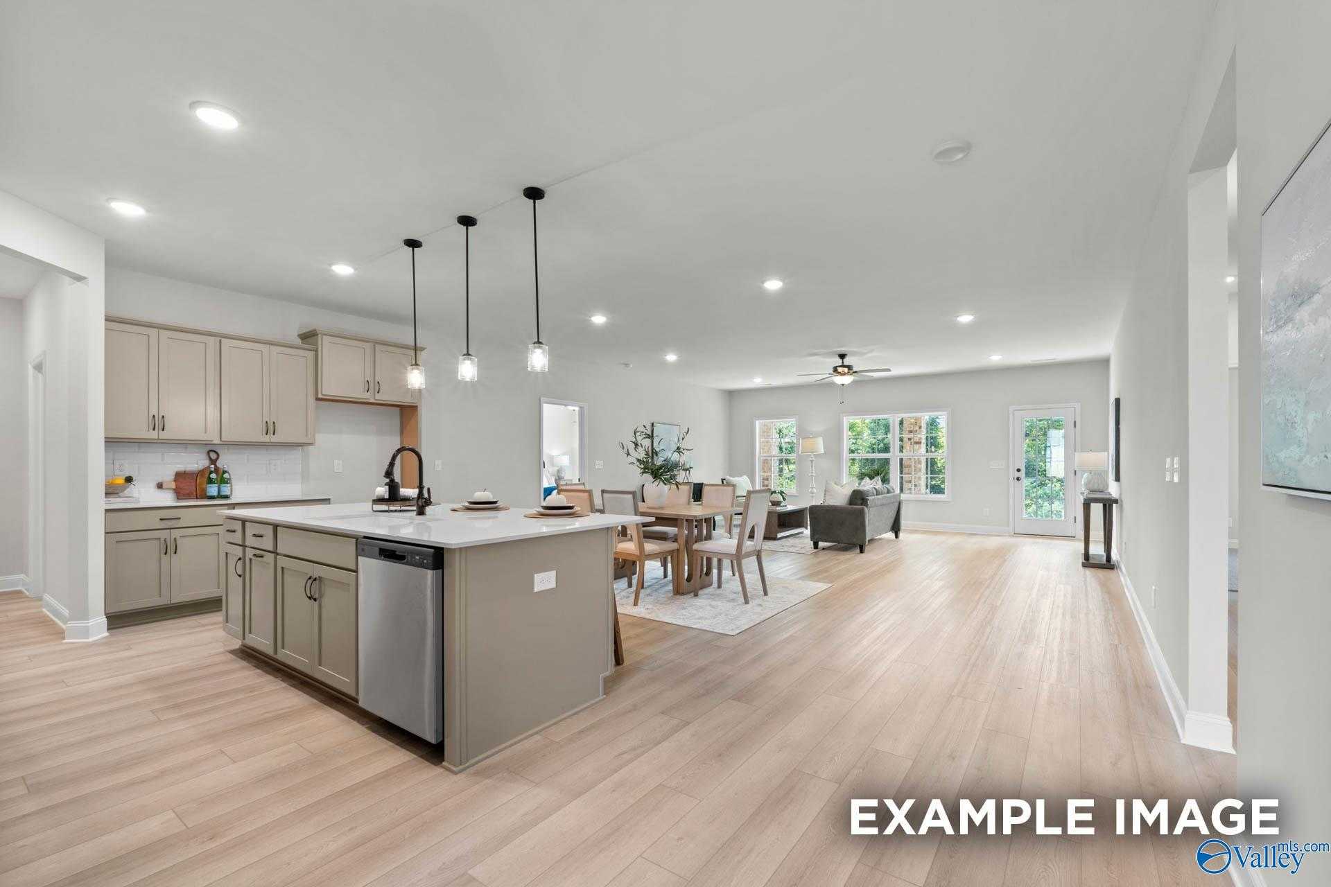 Open-concept kitchen with gray cabinets, island, and pendant lights opening to dining and living area in Davidson Homes The Kirkland, Decatur AL