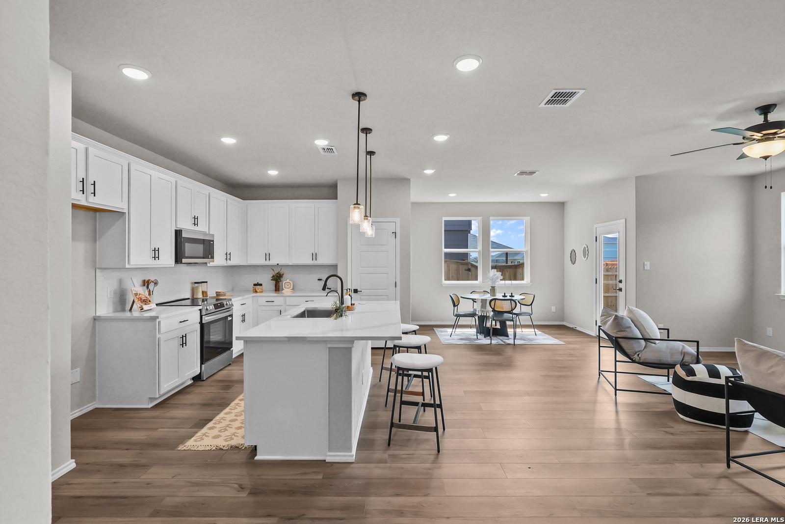Open-concept kitchen with white cabinets and island in The Daphne H floor plan at Hannah Heights, Seguin, Texas.