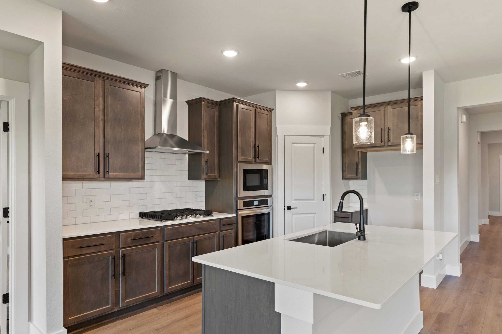 Modern kitchen featuring brown shaker cabinets, stainless steel appliances, white quartz island in Davidson Homes The Everett C, Josephine, Texas