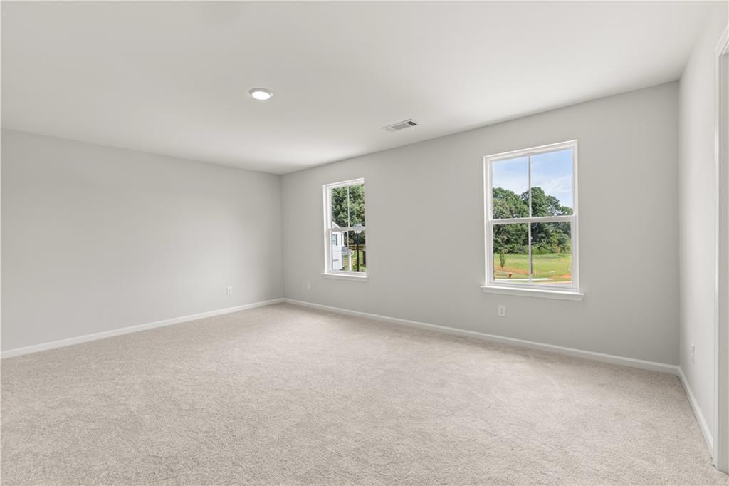 Spacious, light-filled bedroom with plush carpet in The Russell A floor plan at Cedar Farms, Winder, Georgia.