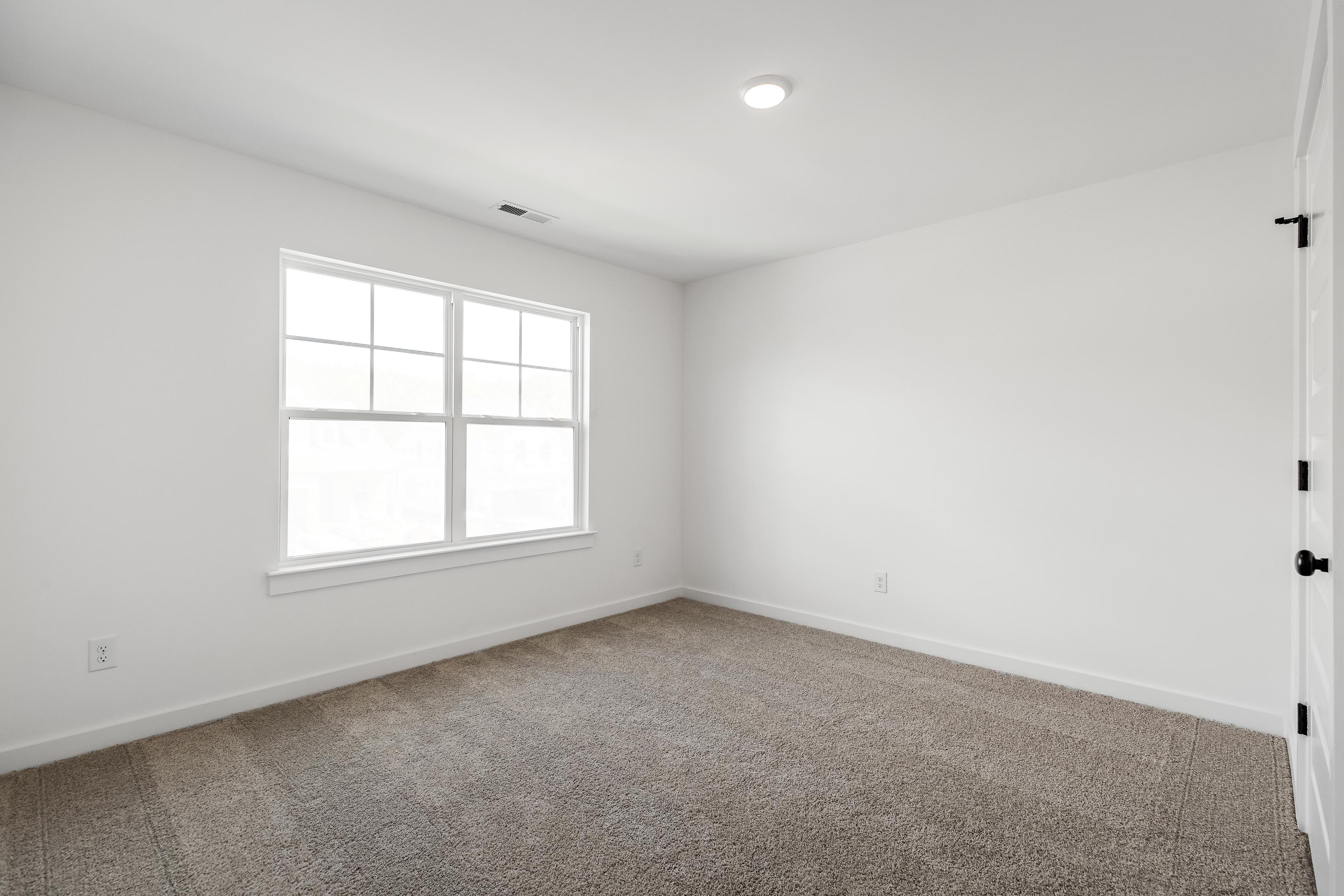 Bright, carpeted bedroom in The Cedar D floor plan by Davidson Homes featuring neutral walls and natural light.