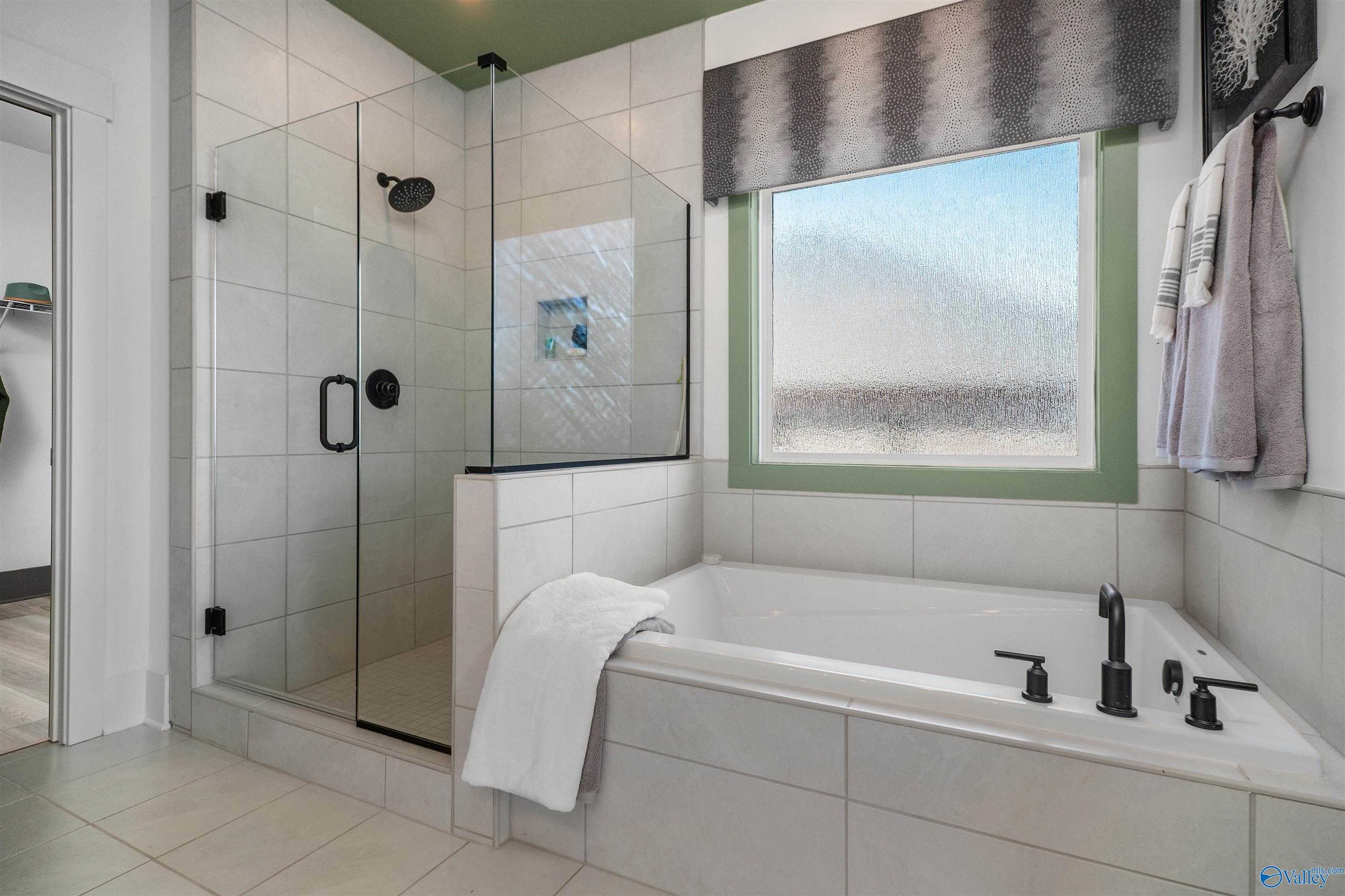 Elegant master bath with frameless glass shower, deep soaking tub, and frosted window in Davidson Homes The Rockford B, Madison AL