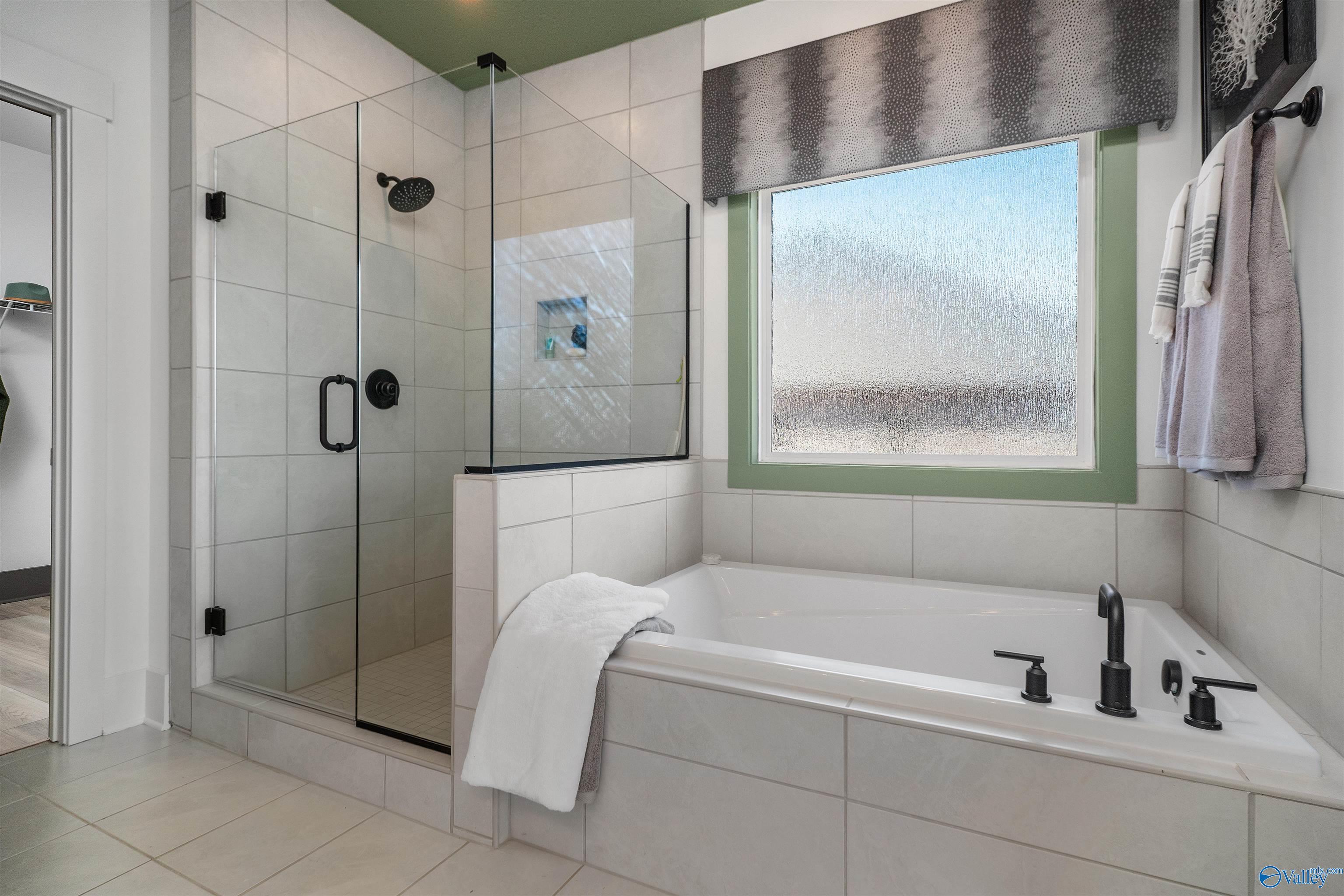 Modern master bathroom with frameless glass shower, soaking tub, and frosted window in Davidson Homes The Rockford B, Madison Alabama