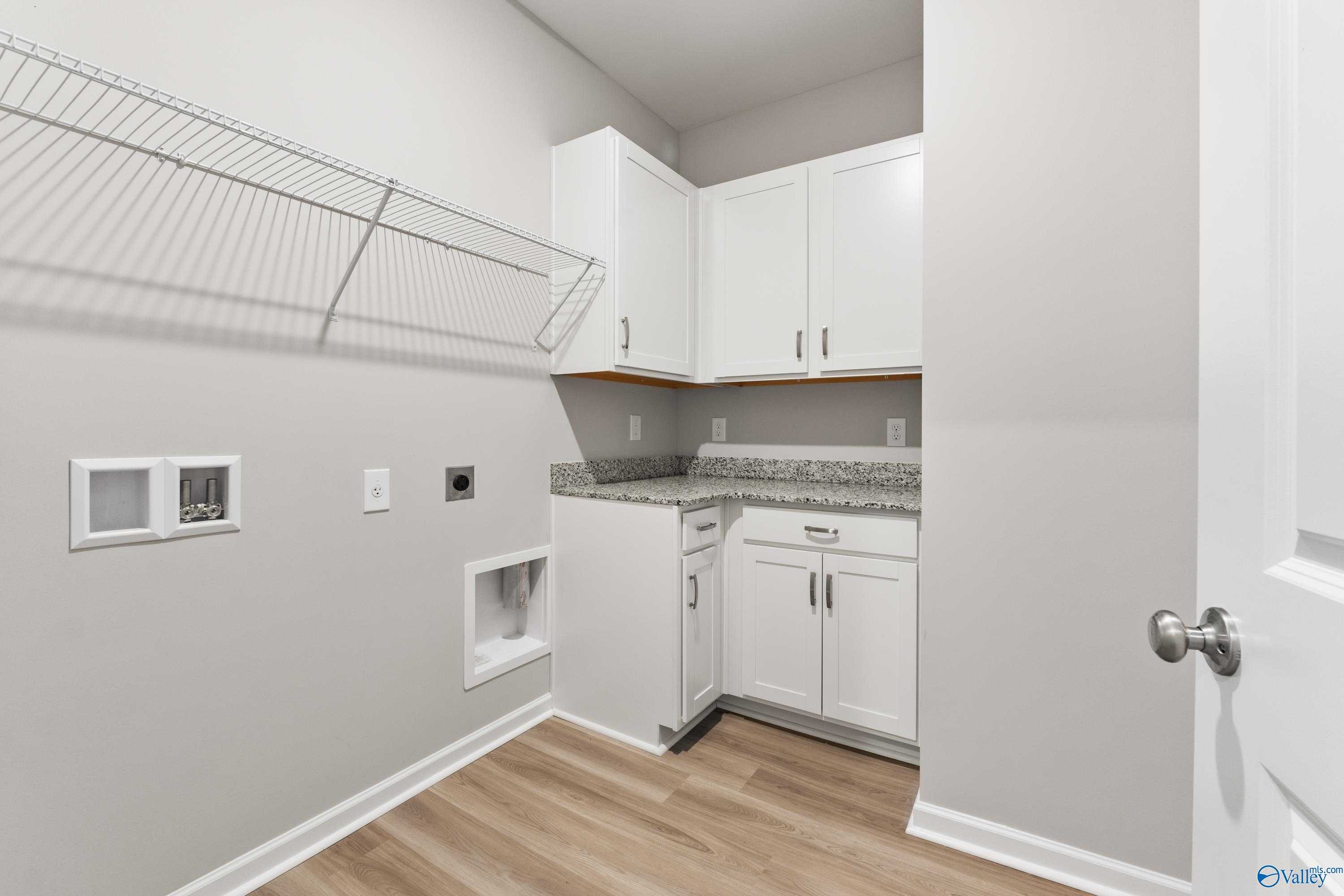 Modern laundry room with white cabinets, granite counter, wire shelving in Davidson Homes The Phoenix, Hazel Green, AL