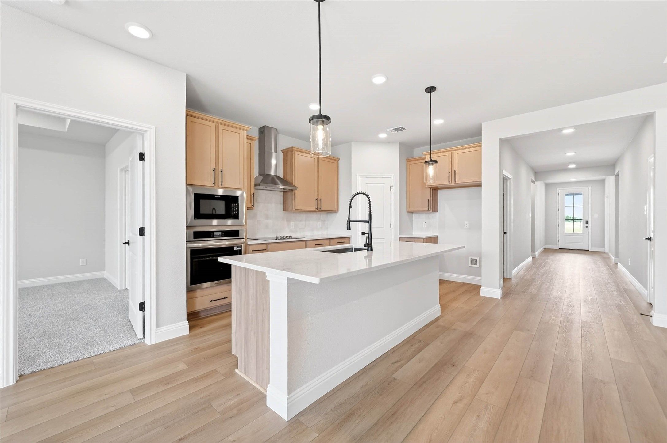 Modern kitchen with large island and stainless appliances in The Holly C floor plan at Parks at Foster Crossing, Anna, TX.